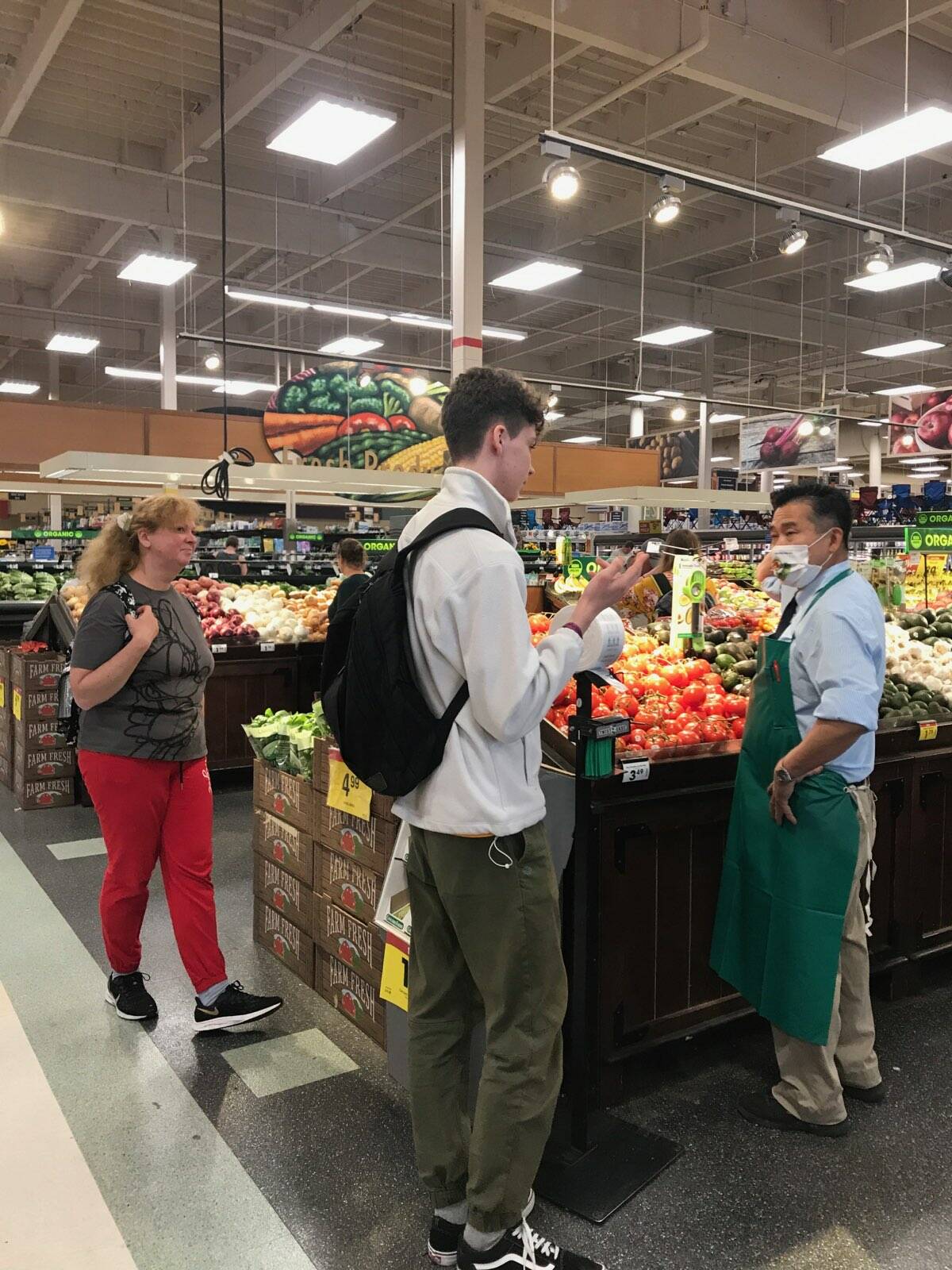 Iryna Hrynchenko and her 18 year old son Ivan, the first refugees from the war in Ukraine to arrive in Juneau, shop for produce at Fred Meyer while talking with an employee who arrived here as a refugee from Vietnam many years ago. (Courtesy Photo / Joyanne Bloom)