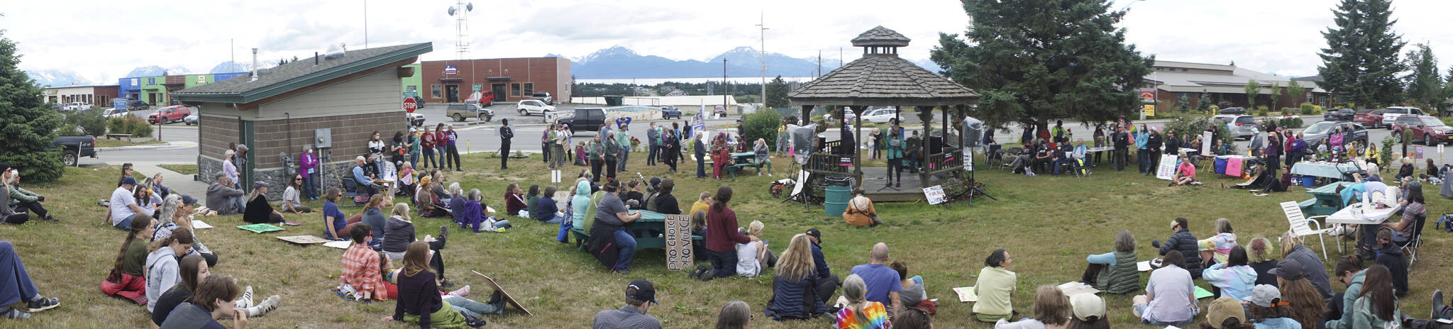 In this panormaic photo, people listen to speakers at the "Women's March: Bans Off Our Bodies" protest on Saturday, July 9, 2022, at WKFL Park in Homer, Alaska. (Photo by Michael Armstrong/Homer News)