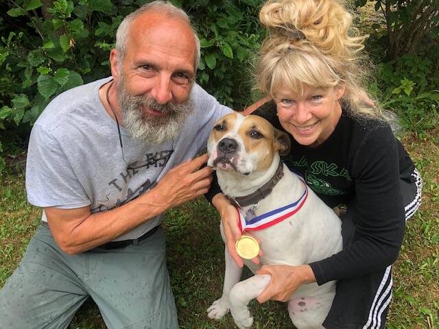 Greg and Teresa Groeneweg pose with their dog, Ace, who is wearing a lifesaver medal Greg received from the Anchorage Fire Department years ago. He said Ace deserves it now more than him, for fighting off a bear. (Courtesy Greg Groeneweg)