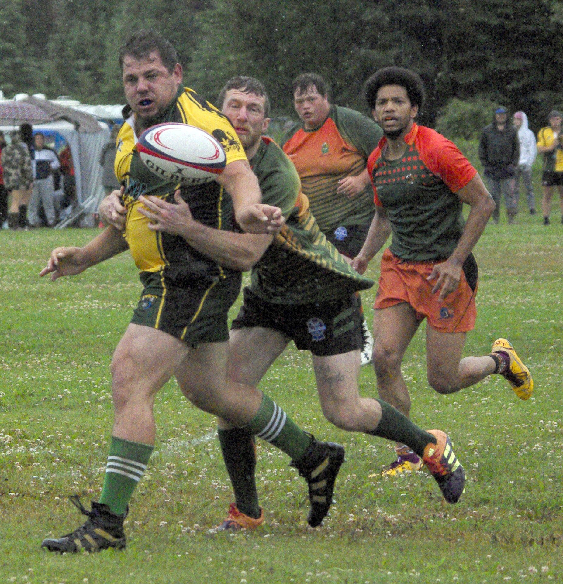 Danny Autrey of the Kenai River Wolfpack passes under pressure from Dalton Morris, Summit Wiman and Cross Gray of the Hermit CRABS at the 2022 Kenai Dipnet Fest Rugby Tournament on Saturday, July 16, 2022, at Millennium Square in Kenai, Alaska. (Photo by Jeff Helminiak/Peninsula Clarion)