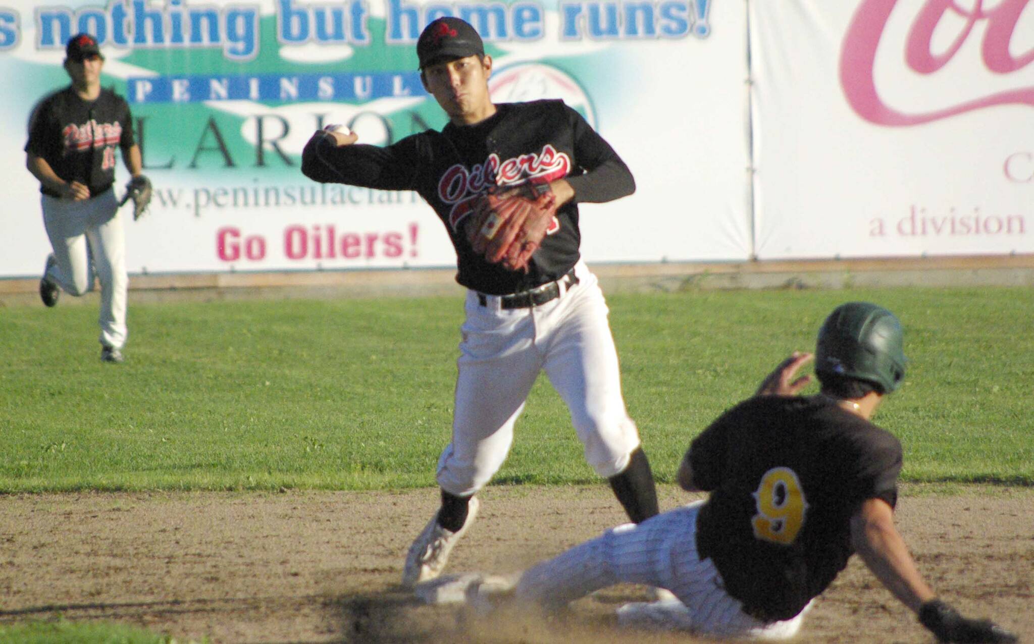 Peninsula Oilers second baseman Shunsuke Sakaino turns a double play as Dom Chacon of the Anchorage Bucs slides Friday, July 22, 2022, at Coral Seymour Memorial Park in Kenai, Alaska. (Photo by Jeff Helminiak/Peninsula Clarion)
