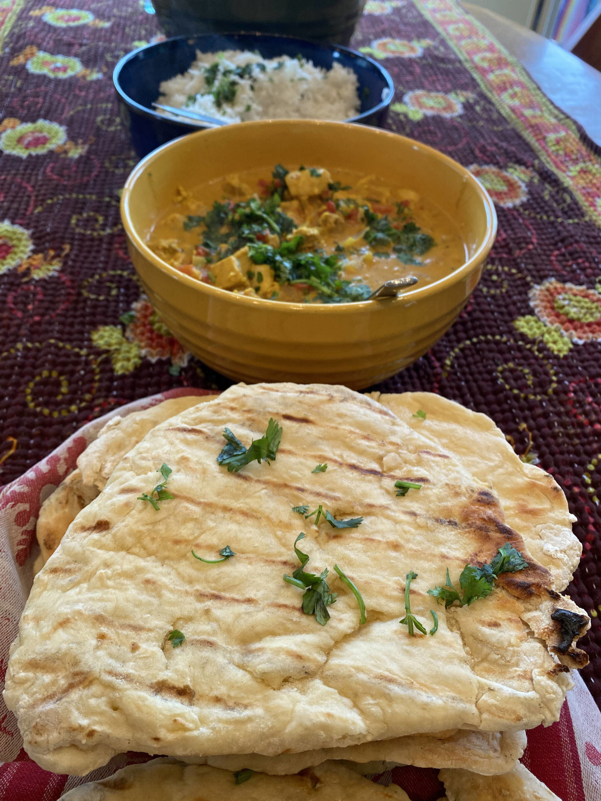 Homemade garlic naan is served with a meal of palak tofu, butter chicken, basmati rice and cucumber salad. (Photo by Tressa Dale/Peninsula Clarion)