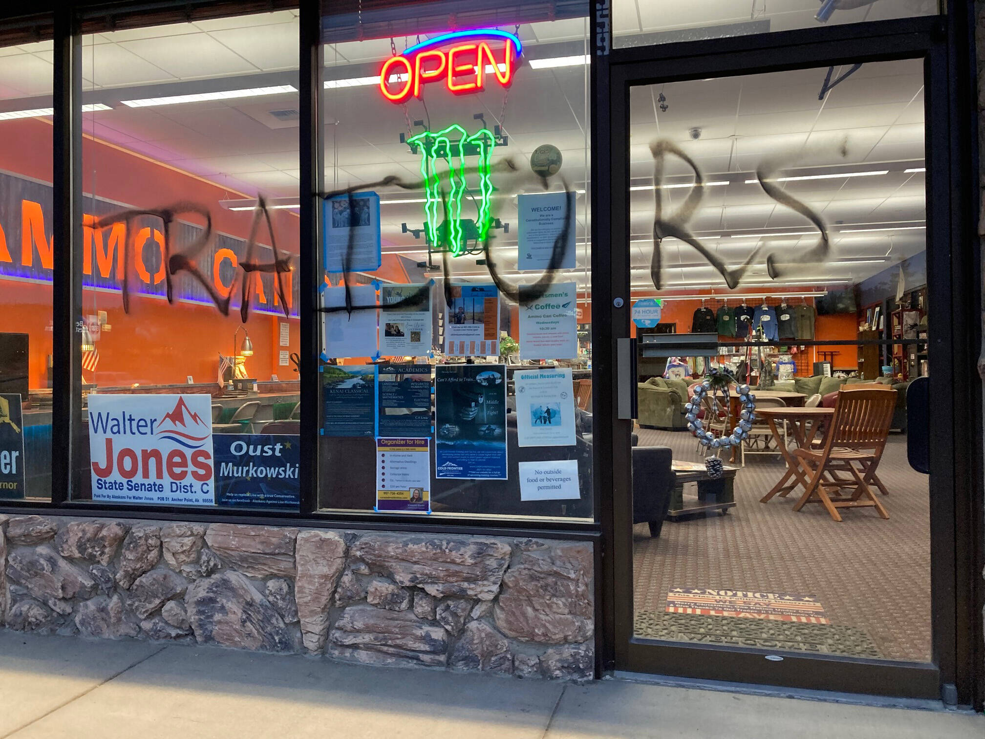 Graffiti can be seen on the front of Ammo-Can Coffee in Soldotna, on Monday, Aug. 8, 2022, in Soldotna, Alaska. The conservative social club and coffee shop reported Monday that someone had vandalized the storefront and glued the locks. (Photo courtesy Ammo-Can Coffee)