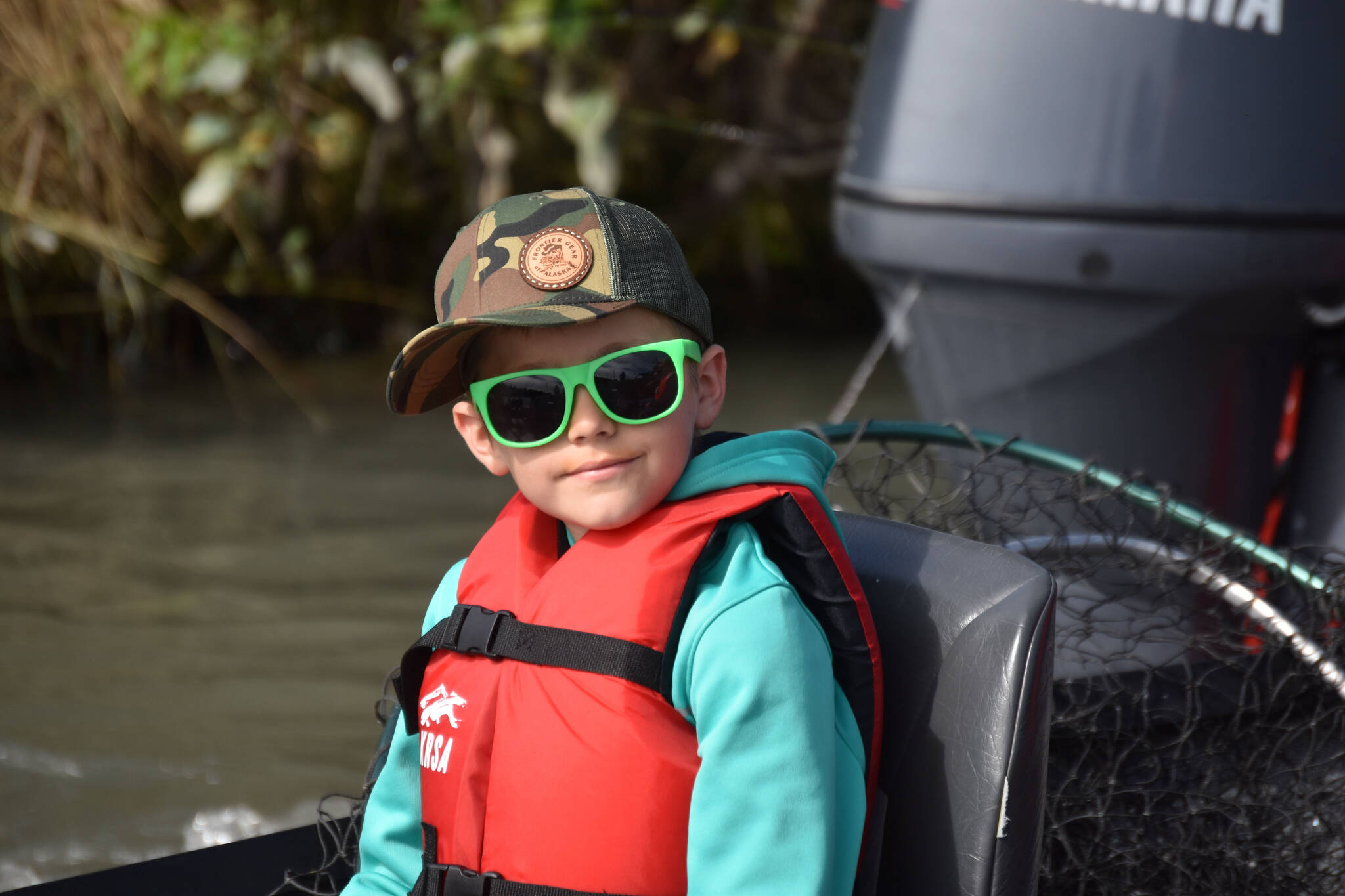 A boy fitted with a life jacket and waiting to go fishing at the Kenai River Junior Classic in Soldotna, Alaska, on Aug. 10, 2022. (Jake Dye/Peninsula Clarion)