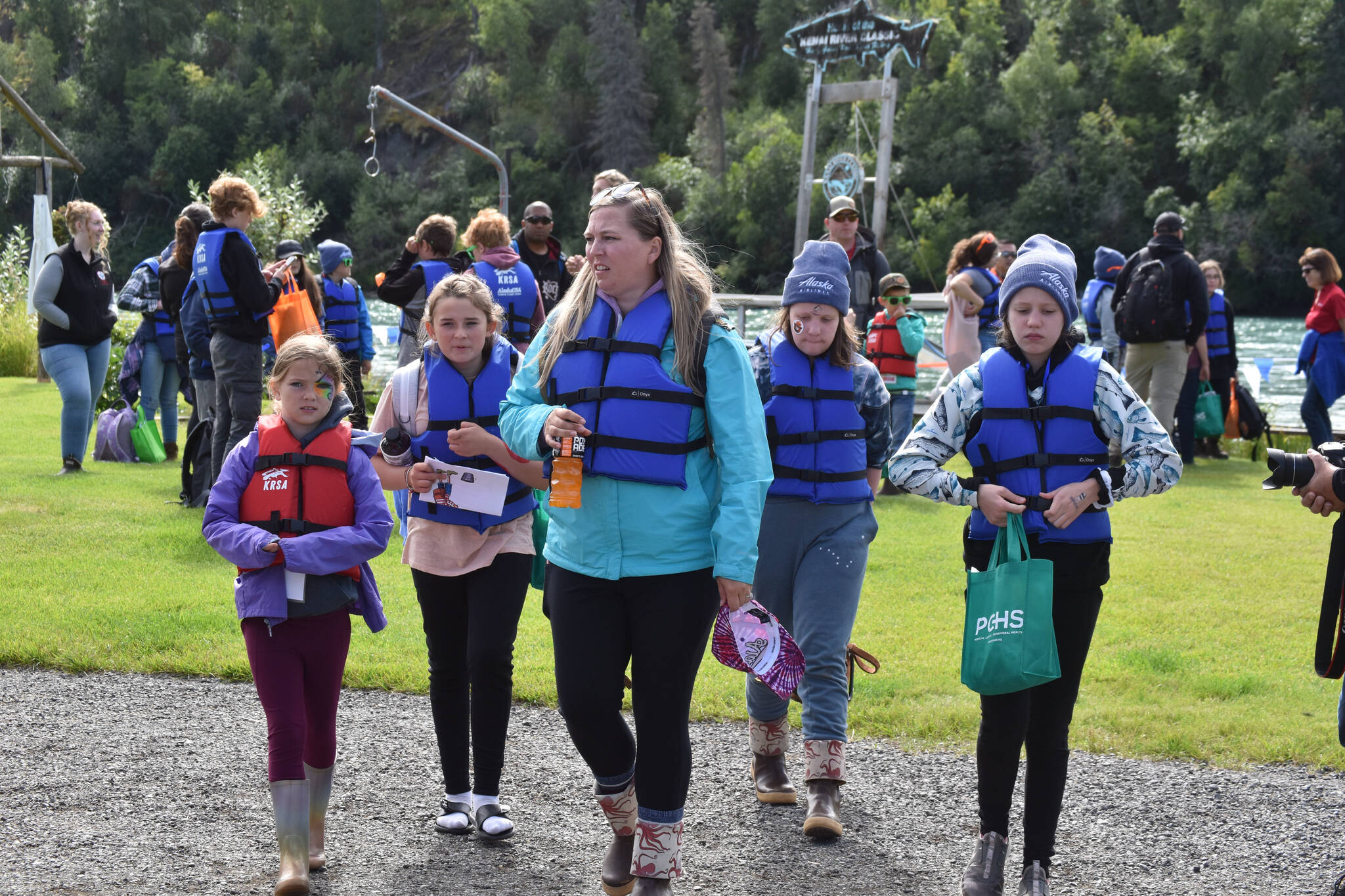 A group of children and a chaperone, fitted with life jackets and waiting to go fishing at the Kenai River Junior Classic in Soldotna, Alaska, on Aug. 10, 2022. (Jake Dye/Peninsula Clarion)