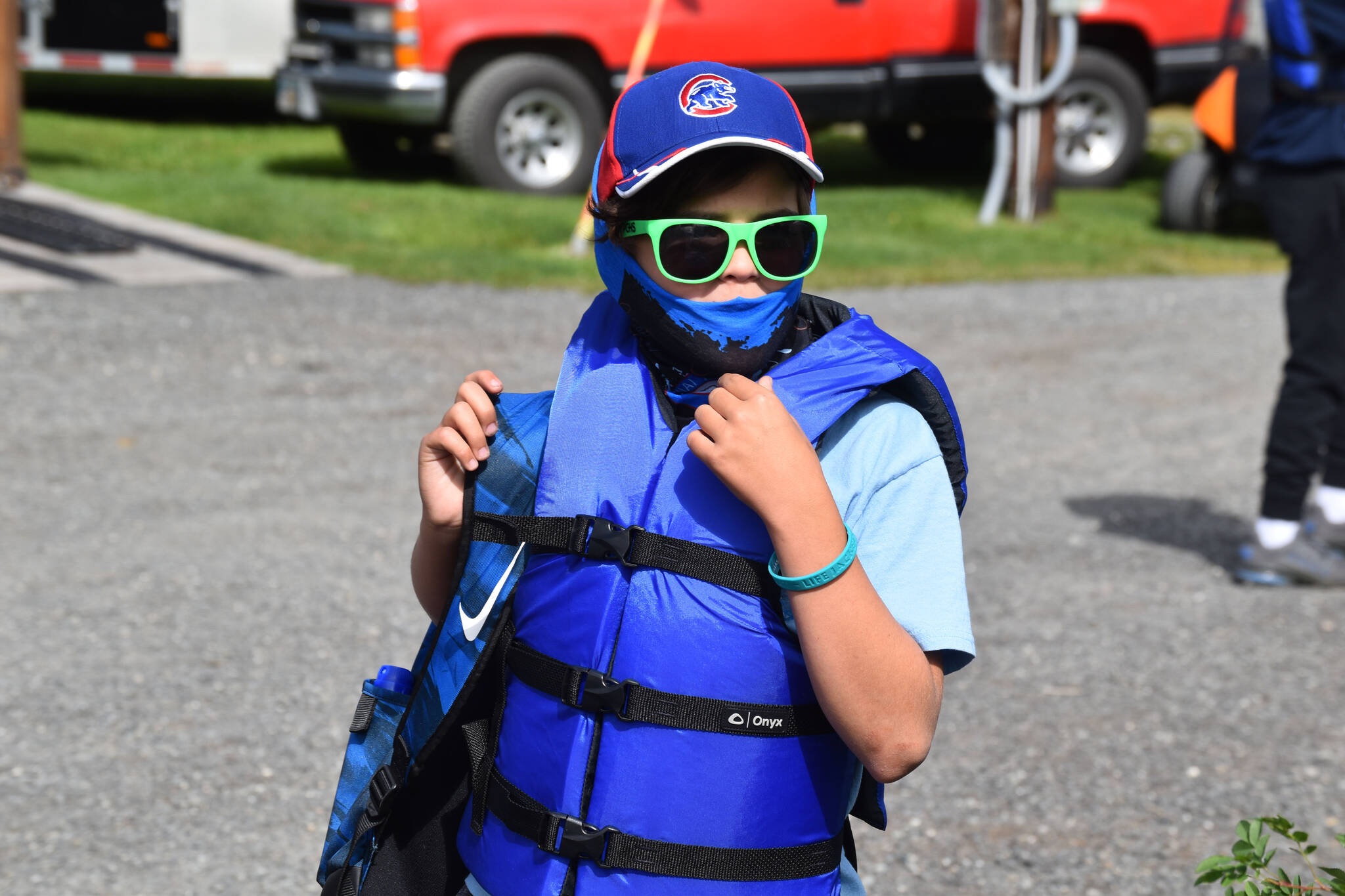 A boy fitted with a life jacket and waiting to go fishing at the Kenai River Junior Classic in Soldotna, Alaska, on Aug. 10, 2022. (Jake Dye/Peninsula Clarion)