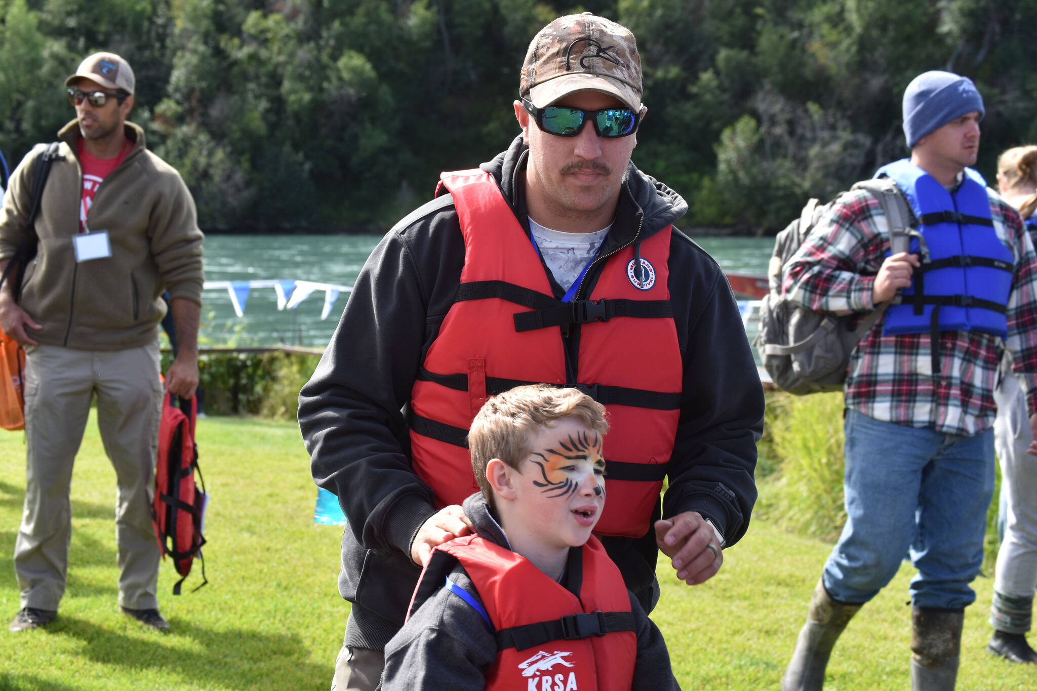 A boy and chaperone fitted with life jackets and waiting to go fishing at the Kenai River Junior Classic in Soldotna, Alaska, on Aug. 10, 2022. (Jake Dye/Peninsula Clarion)