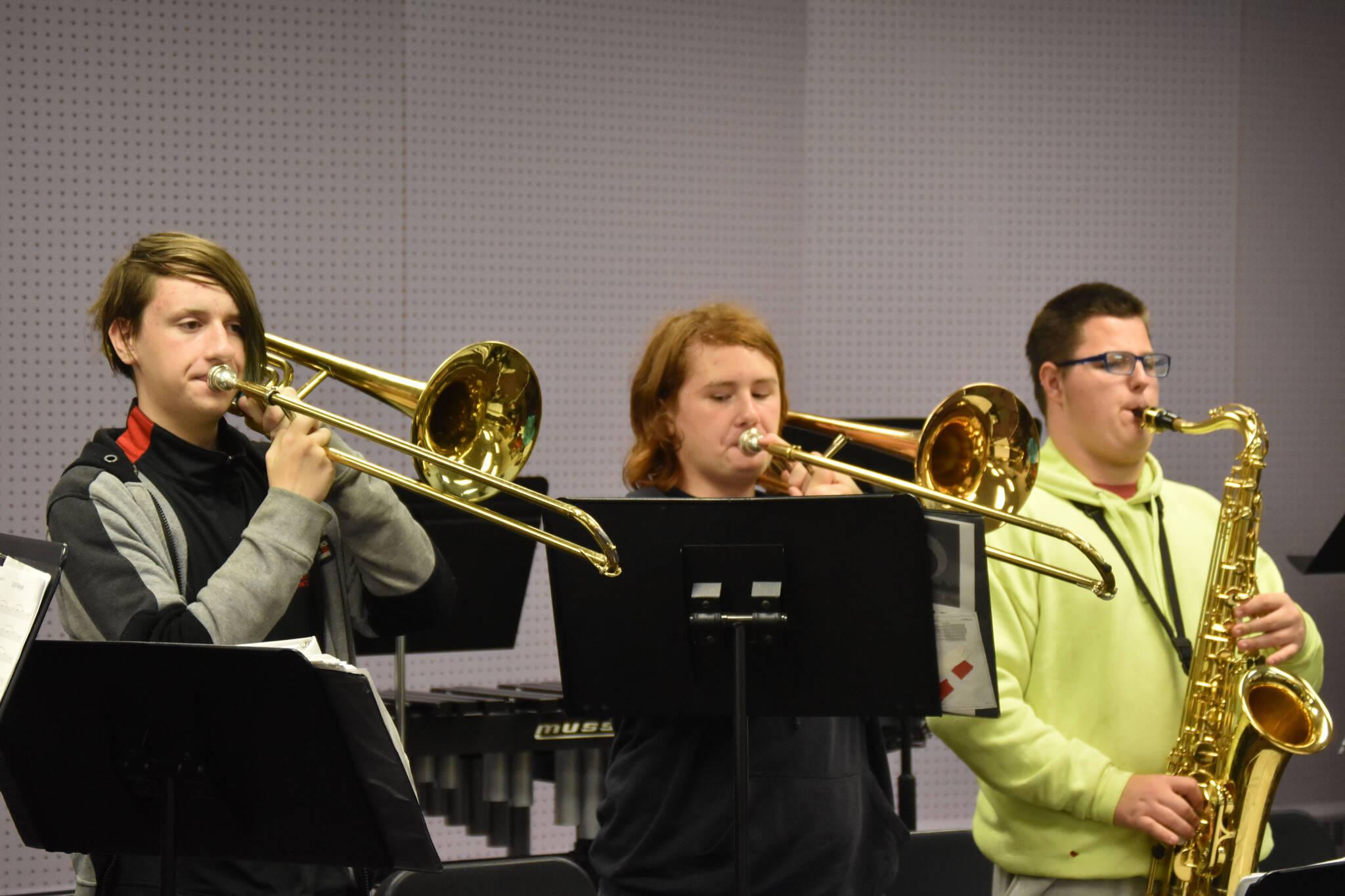 Two trombone players and a saxophone perform during a KCHS Marching Band practice on Aug. 18, 2022, in Kenai, Alaska. (Jake Dye/Peninsula Clarion)