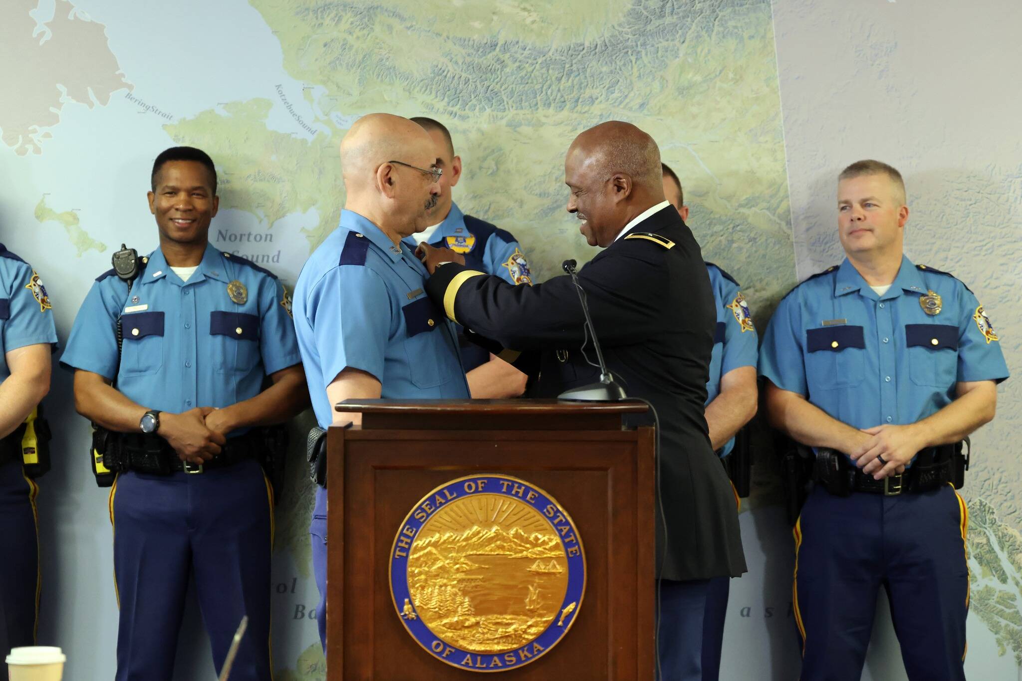 Alaska Defense Force Brig. Gen. Simon Brown pins a badge on Maurice “Mo” Hughes, left, who was promoted from commander of A Detachment to colonel of the Alaska State Troopers during a press conference on Wednesday, Aug. 31, 2022, in Anchorage, Alaska. (Photo courtesy Alaska State Troopers)