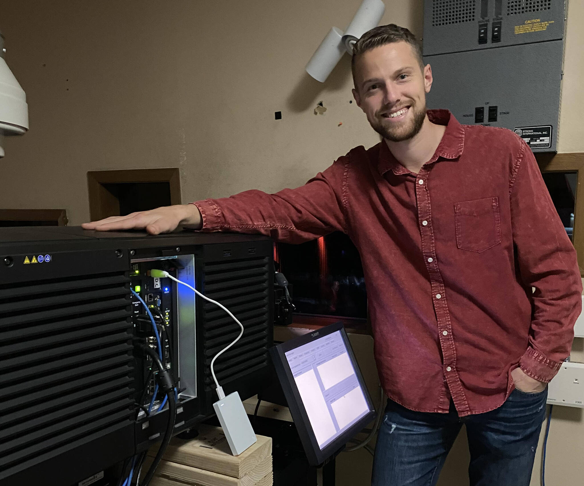 Josiah Martin, of Soldotna production company Martin Media, is seen in the projection booth at Kenai Cinema on Tuesday, Sept. 6, 2022, in Kenai, Alaska. Triumvirate partnered with Martin to produce the film. (Photo courtesy Joe Rizzo)