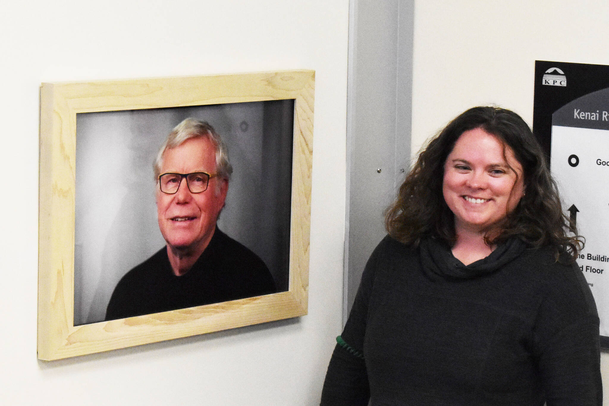 Kenai Peninsula College Advancement Programs Manager Alasha Brito unveils a new framed photo that hangs at the entryway of the newly dedicated Alan ‘Tiqutsex’ Boraas Anthropology Lab at KPC on Friday, Sept. 16, 2022, in Soldotna, Alaska. A new plaque and a piece of artwork to commemorate Boraas also hang by the entryway. (Jake Dye/Peninsula Clarion)