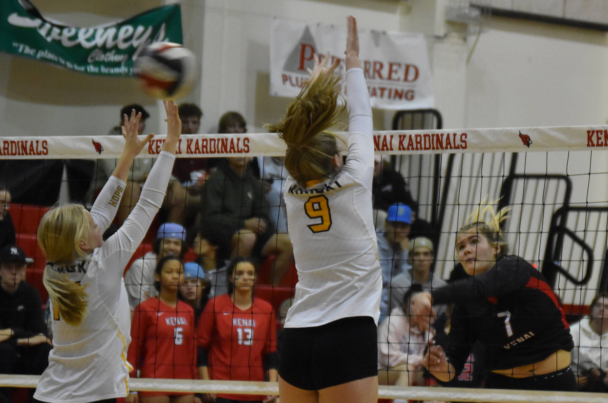 Avery White and Ashlynne Playle leap to block a spike from Emma Beck on Thursday, Sept. 22, 2022 at Kenai Central High School in Kenai, Alaska. (Jake Dye/Peninsula Clarion)