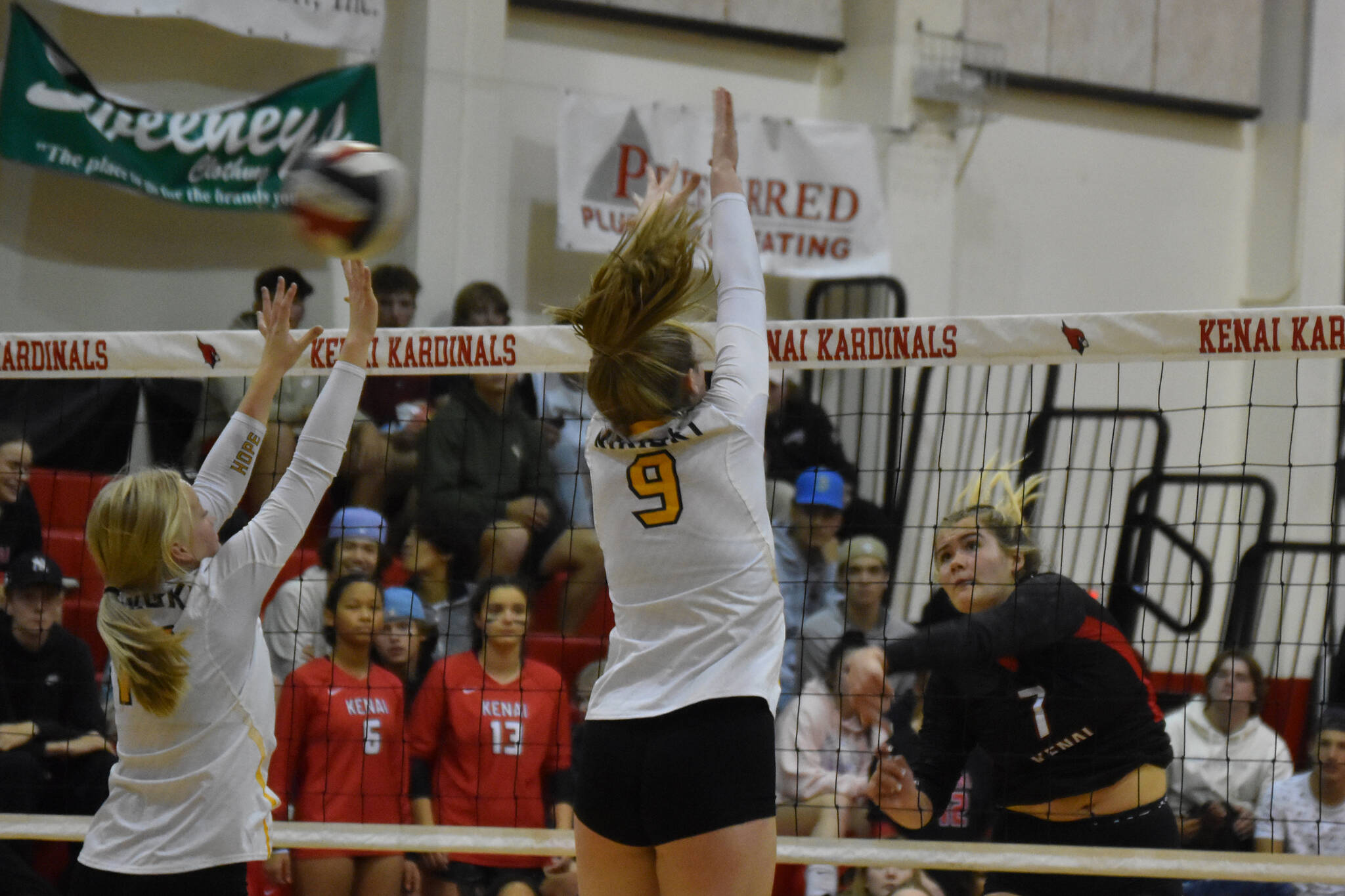 Avery White and Ashlynne Playle leap to block a spike from Emma Beck on Thursday, Sept. 22, 2022 at Kenai Central High School in Kenai, Alaska. (Jake Dye/Peninsula Clarion)