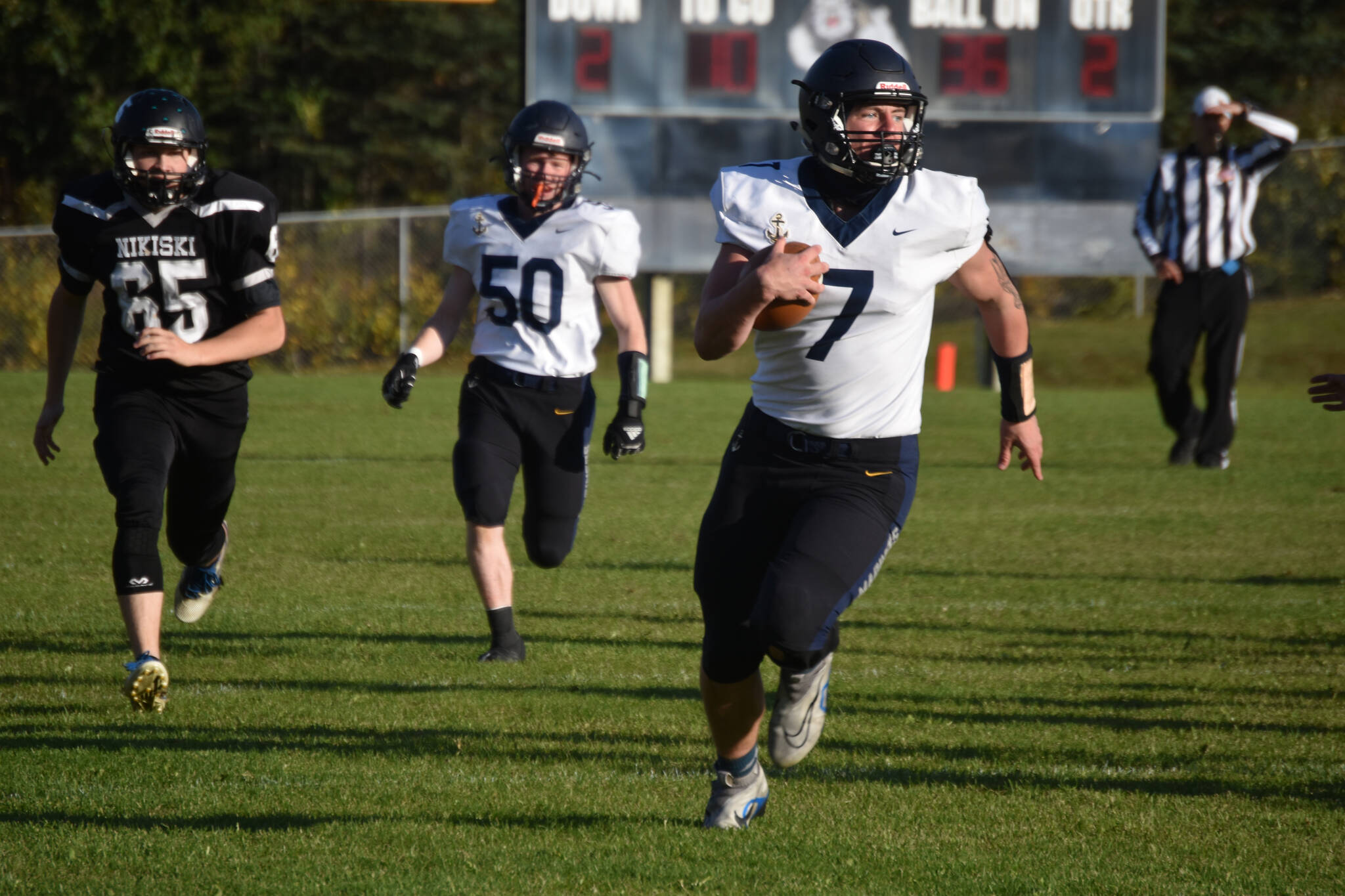 Homer’s Carter Tennison runs with the ball, pursued by Nikiski’s Drake Brankel, on Friday, Sept. 23, 2022, at Nikiski High School in Nikiski, Alaska. (Jake Dye/Peninsula Clarion)