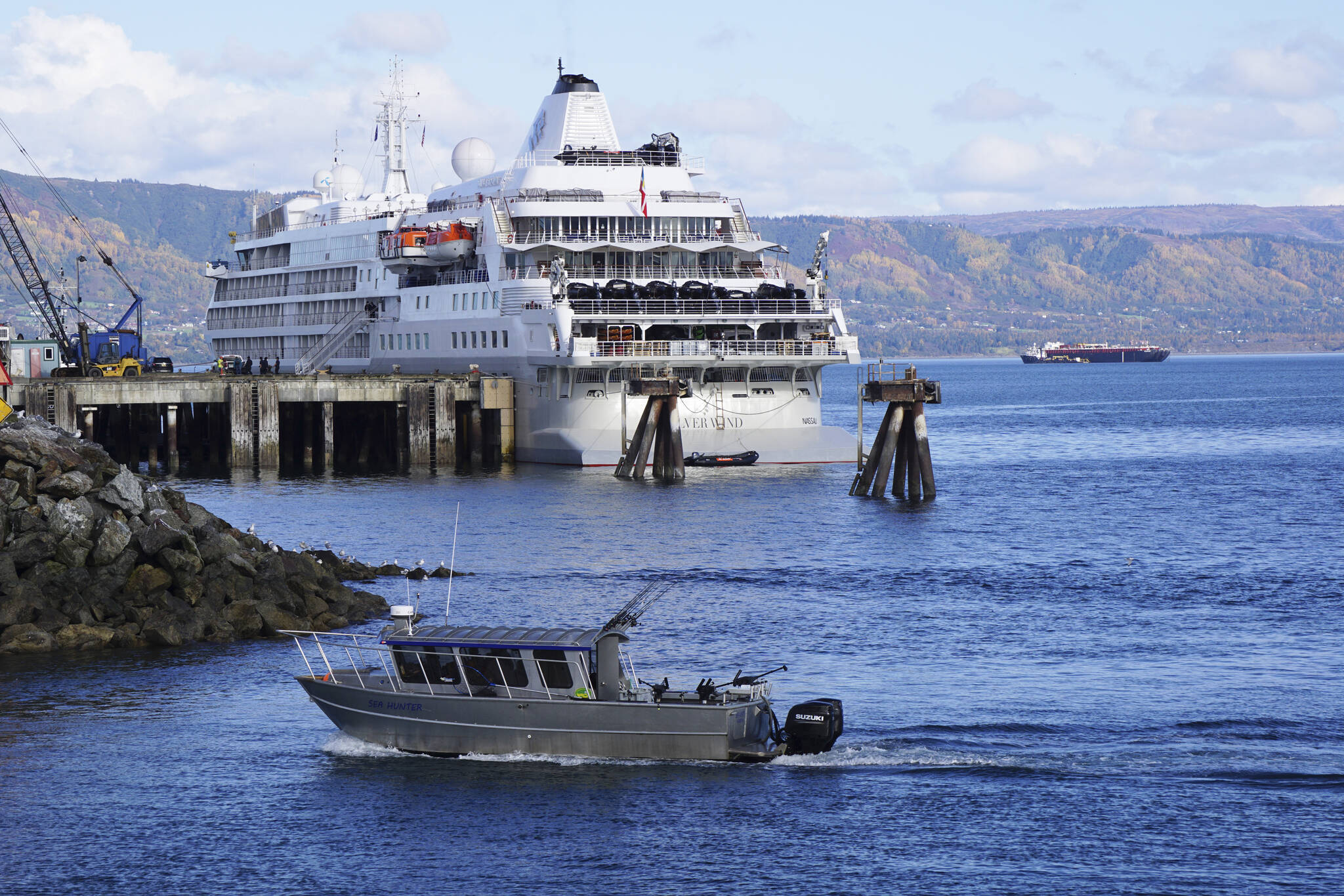 A fishing boat passes the Silversea cruise ship Silver Wind as the boat enters the Homer Harbor on Sunday, Sept. 25, 2022, in Homer, Alaska. (Photo by Michael Armstrong/Homer News)