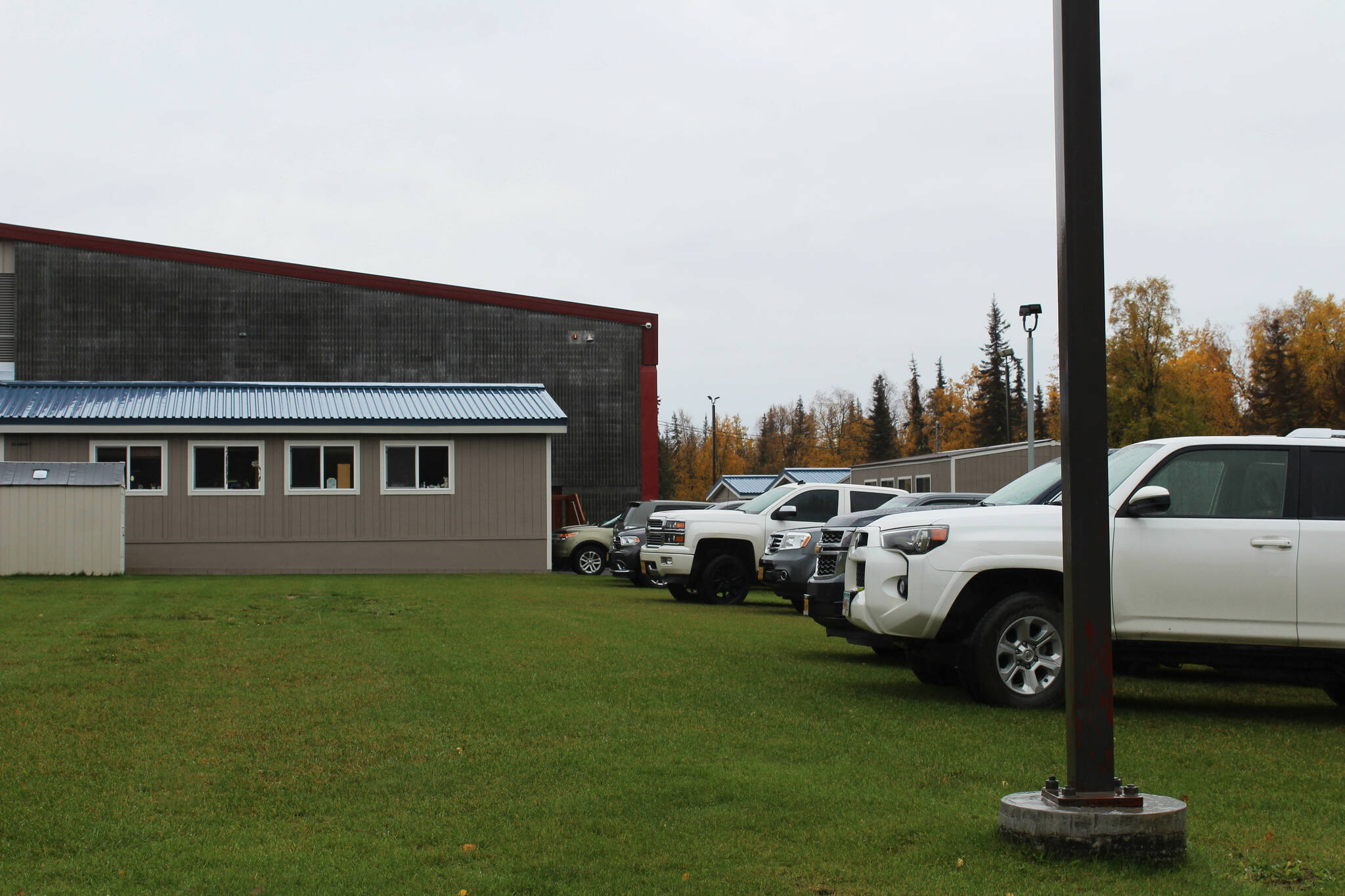 Staff vehicles are parked on the grass behind Mountain View Elementary School on Thursday, Sept. 29, 2022 in Kenai, Alaska. A bond package up for consideration by Kenai Peninsula Borough voters on Oct. 4 would fund improvements to the school’s traffic flow. (Ashlyn O’Hara/Peninsula Clarion)