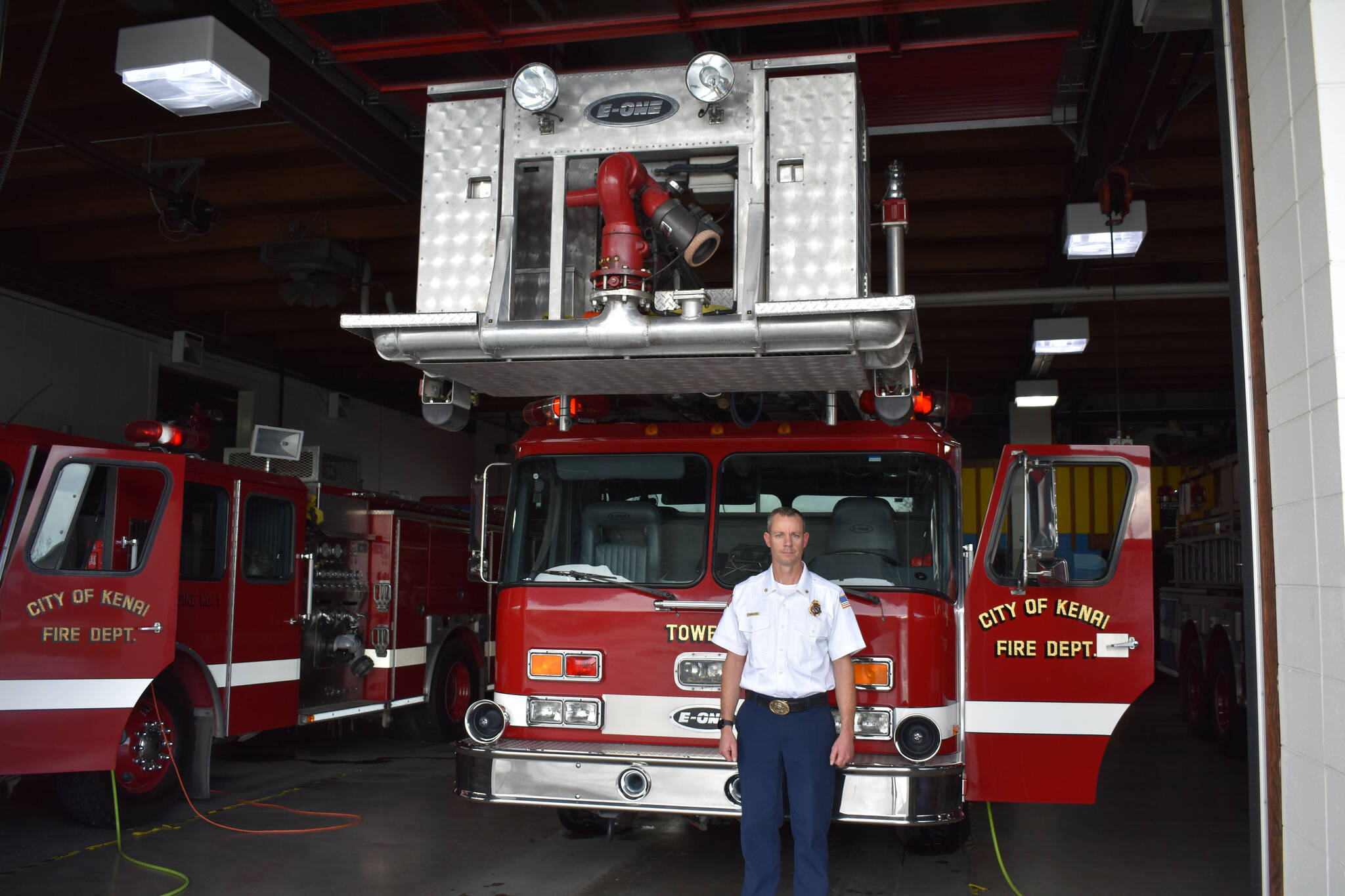 Kenai Fire Marshal Jeremy Hamilton is seen by one of Kenai Fire Department’s Tower trucks on Friday, Sept. 30, 2022 at Kenai Fire Department in Kenai, Alaska. (Jake Dye/Peninsula Clarion)