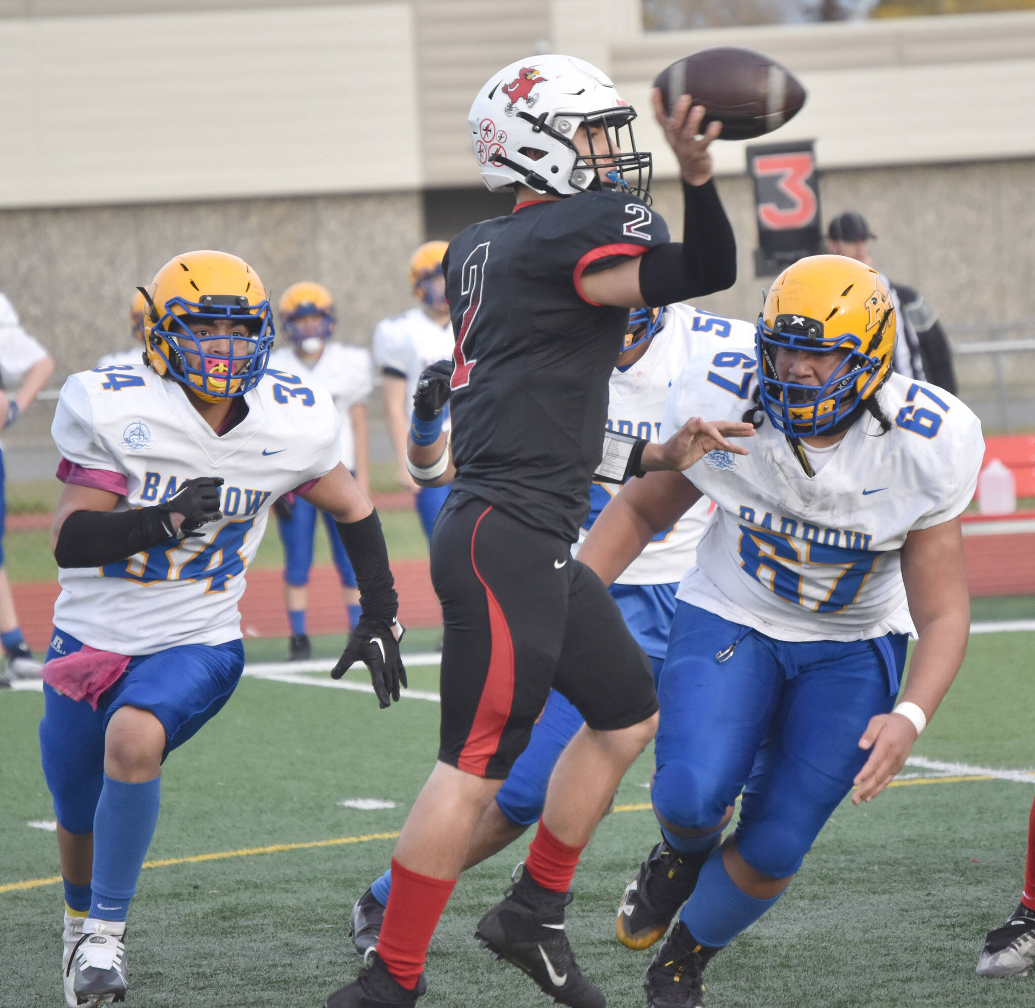 Kenai Central’s Bridger Beck passes under pressure from Barrow’s Lennox Dias and Norm Lilomaiava on Saturday, Oct. 1, 2022, at Ed Hollier Field at Kenai Central High School in Kenai, Alaska. (Photo by Jeff Helminiak/Peninsula Clarion)