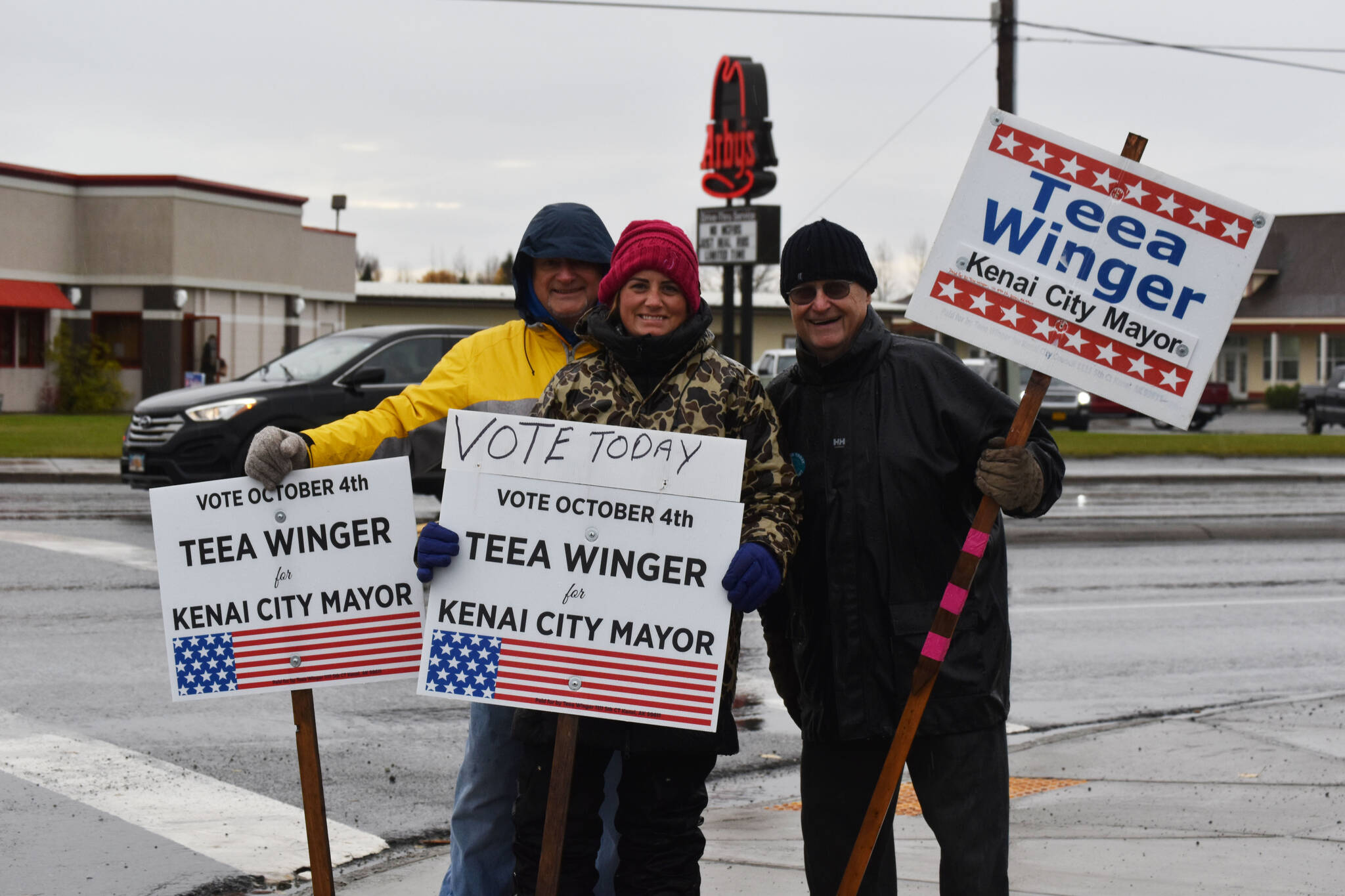 Mike McBride, Teea Winger and Jim Glendening wave signs on Election Day, Oct. 4, 2022, in Kenai, Alaska. (Jake Dye/Peninsula Clarion)