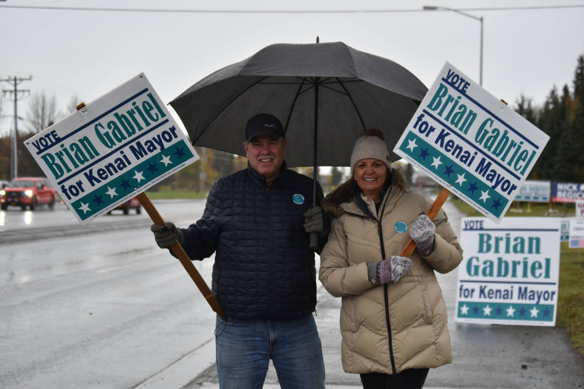 Brian Gabriel and Lisa Gabriel wave signs on Election Day, Oct. 4, 2022, in Kenai, Alaska. (Jake Dye/Peninsula Clarion)