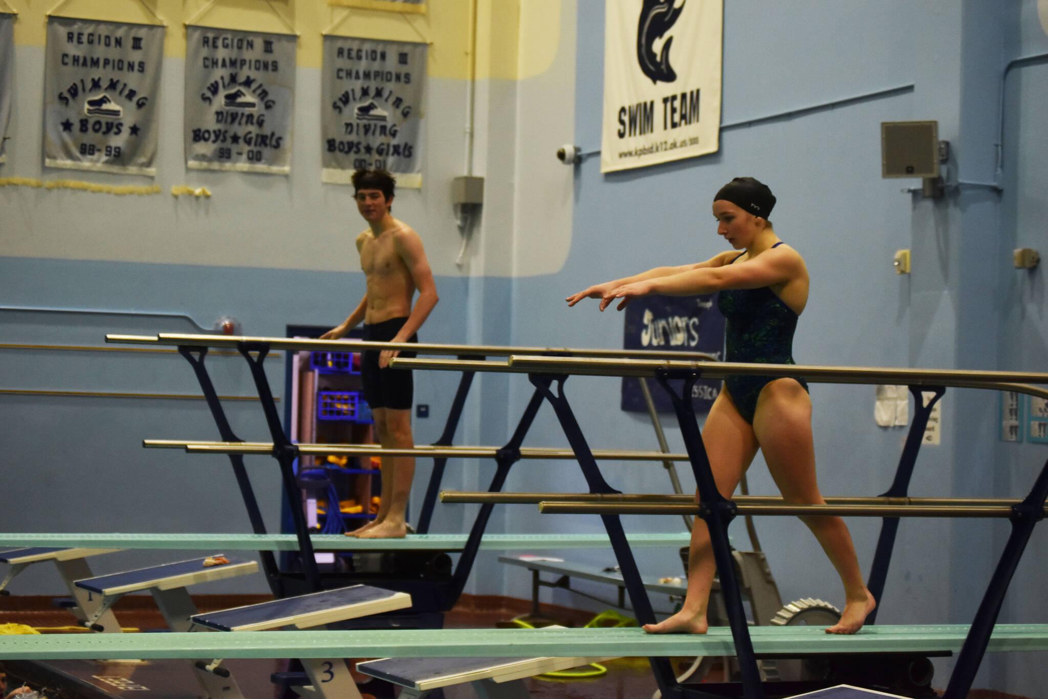 Abriella Werner approaches the end of the diving board, Derrick Jones watches during a dive practice on Tuesday, Oct. 11, 2022, at Soldotna High School in Soldotna, Alaska. (Jake Dye/Peninsula Clarion)