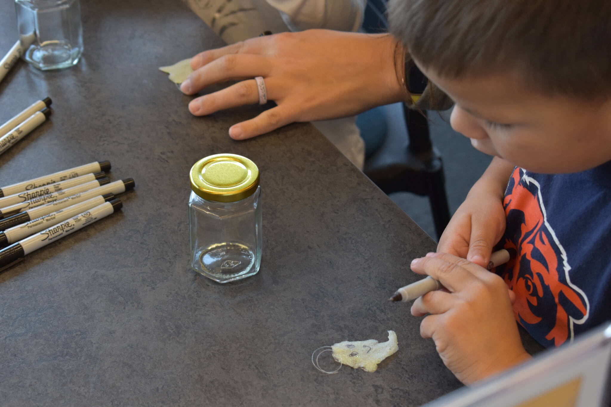 Kids draw faces on their new pet ghosts at the Kenai Community Library in Kenai, Alaska on Friday, Oct. 14, 2022. (Jake Dye/Peninsula Clarion)