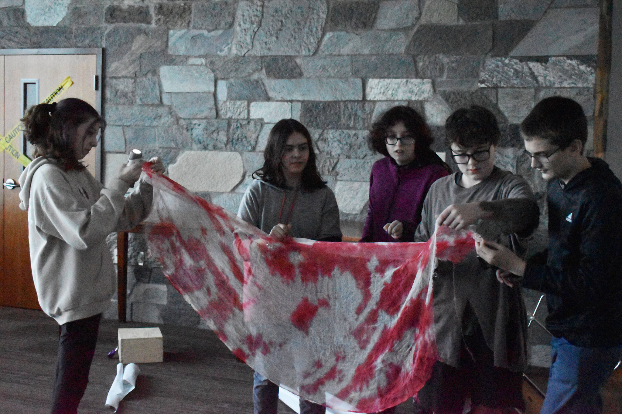 Teens search a piece of — fake — bloodied gauze for the pieces to a combination in an escape room on Oct. 21, 2022, at Soldotna Public Library in Soldotna, Alaska. (Jake Dye/Peninsula Clarion)