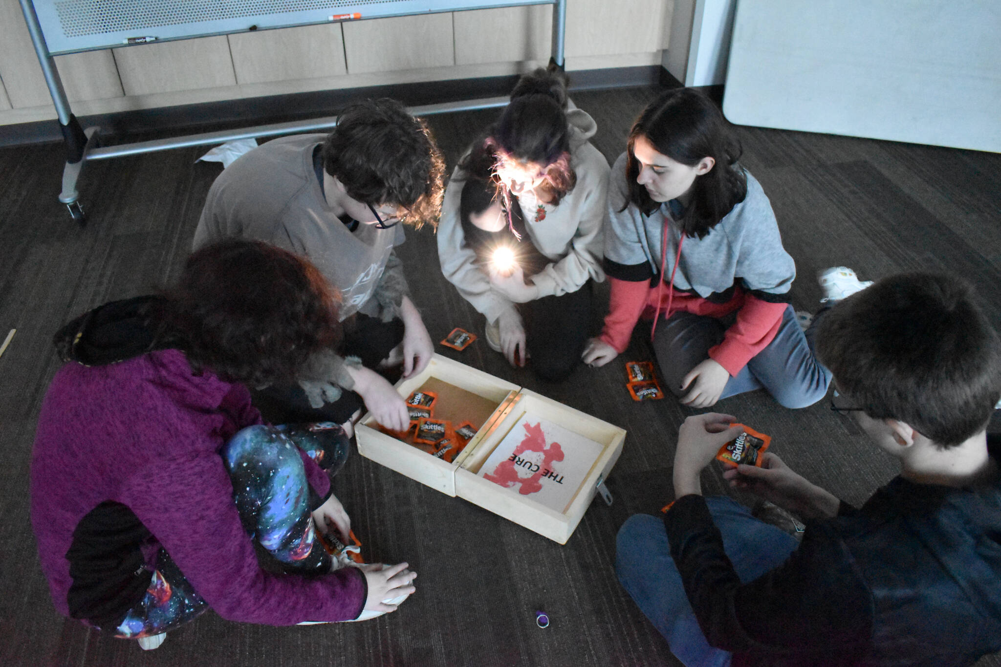 Teens distribute the zombie cure — Zombie Skittles — after completing the escape room on Oct. 21, 2022, at Soldotna Public Library in Soldotna, Alaska. (Jake Dye/Peninsula Clarion)