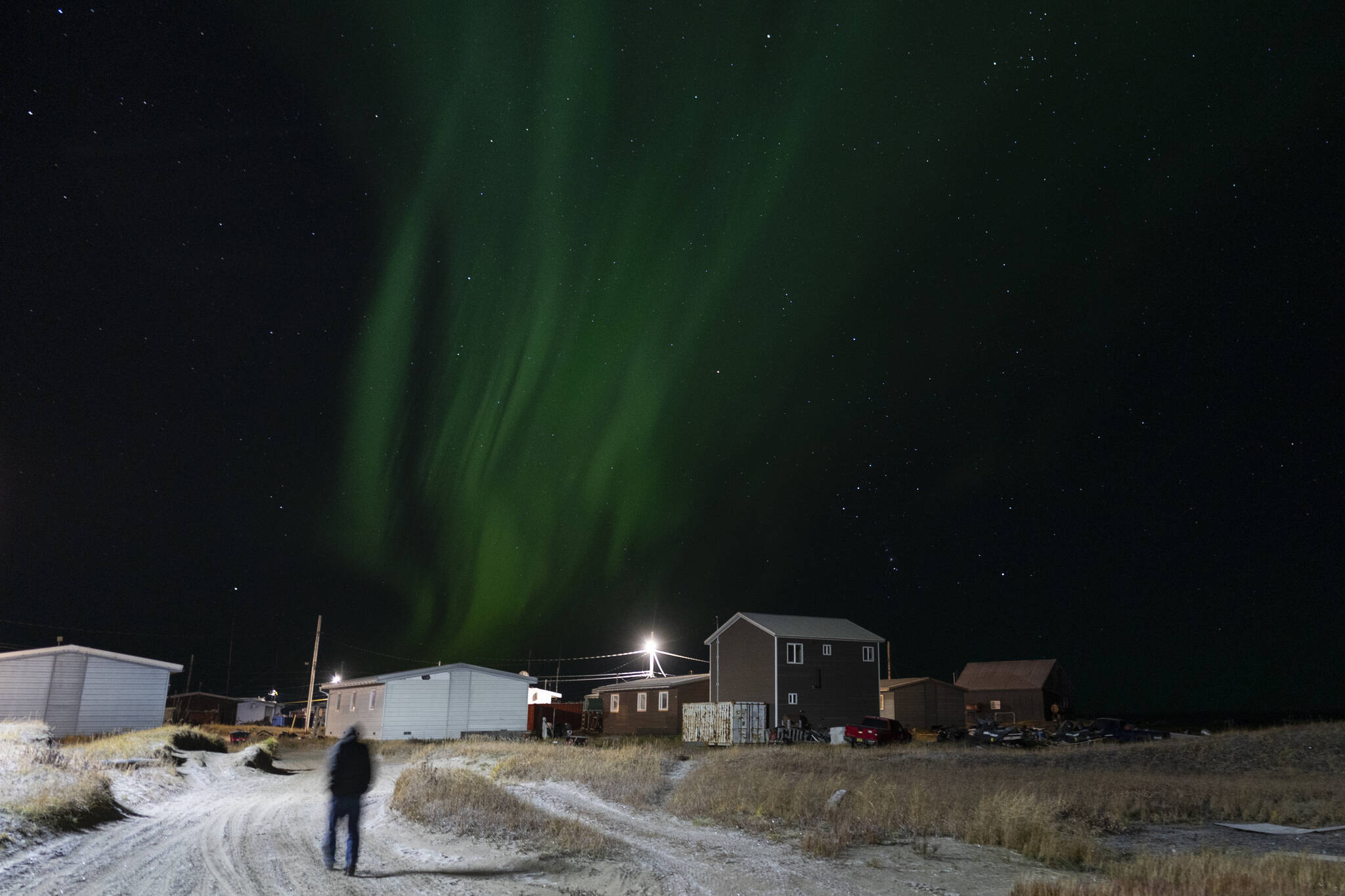 The northern lights appear over Shishmaref, Alaska, Sunday, Oct. 2, 2022. Rising sea levels, flooding, increased erosion and loss of protective sea ice and land have led residents of this island community to vote twice to relocate. But more than six years after the last vote, Shishmaref remains in the same place because the relocation is too costly. (AP Photo/Jae C. Hong)