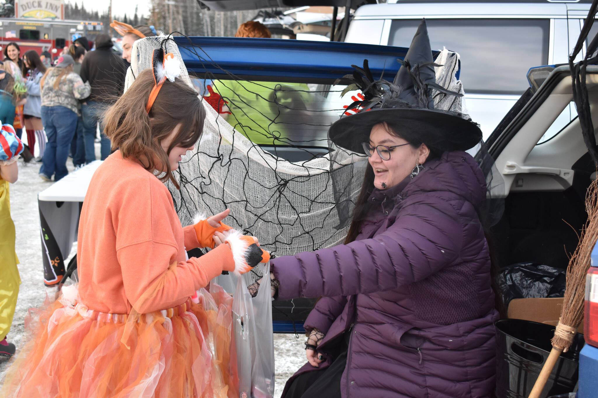 A girl dressed as a fox takes candy from a witch at the Orca Theater’s Trunk or Treat in Soldotna, Alaska, on Monday, Oct. 31, 2022. (Jake Dye/Peninsula Clarion)