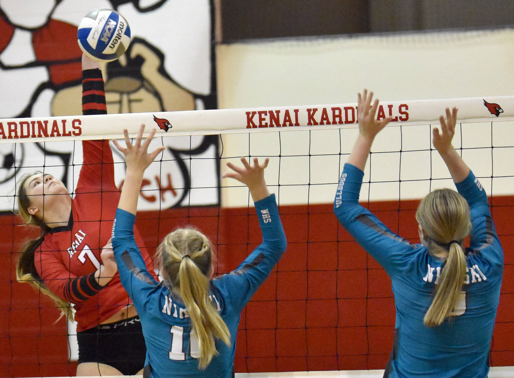 Kenai Central’s Emma Beck attacks the block of Nikiski’s Avery White and Ashlynne Playle on Saturday, Nov. 5, 2022, at the Southcentral Conference volleyball tournament at Kenai Central High School in Kenai, Alaska. (Photo by Jeff Helminiak/Peninsula Clarion)
