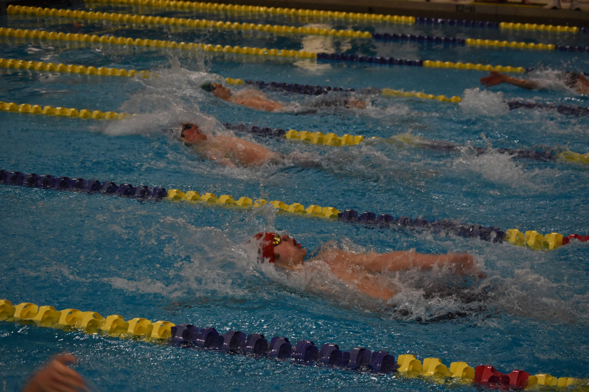 Samuel Anderson (closest), of Kenai, Wesley Mank, of Eagle River, and William Kitchen, of Service High School, swim the 100-yard backstroke during finals at the ASAA State Swim & Dive Championships on Saturday, Nov. 5, 2022, at Bartlett High School in Anchorage, Alaska. (Jake Dye/Peninsula Clarion)