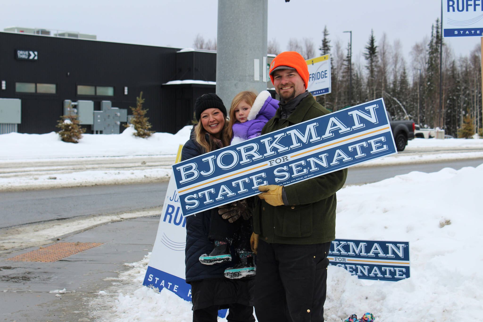 From left, Jamie, Brinna and Jesse Bjorkman wave signs supporting Jesse Bjorkman’s bid for Alaska State Senate at the intersection of the Kenai Spur and Sterling highways on Tuesday, Nov. 8, 2022 in Soldotna, Alaska. (Ashlyn O’Hara/Peninsula Clarion)