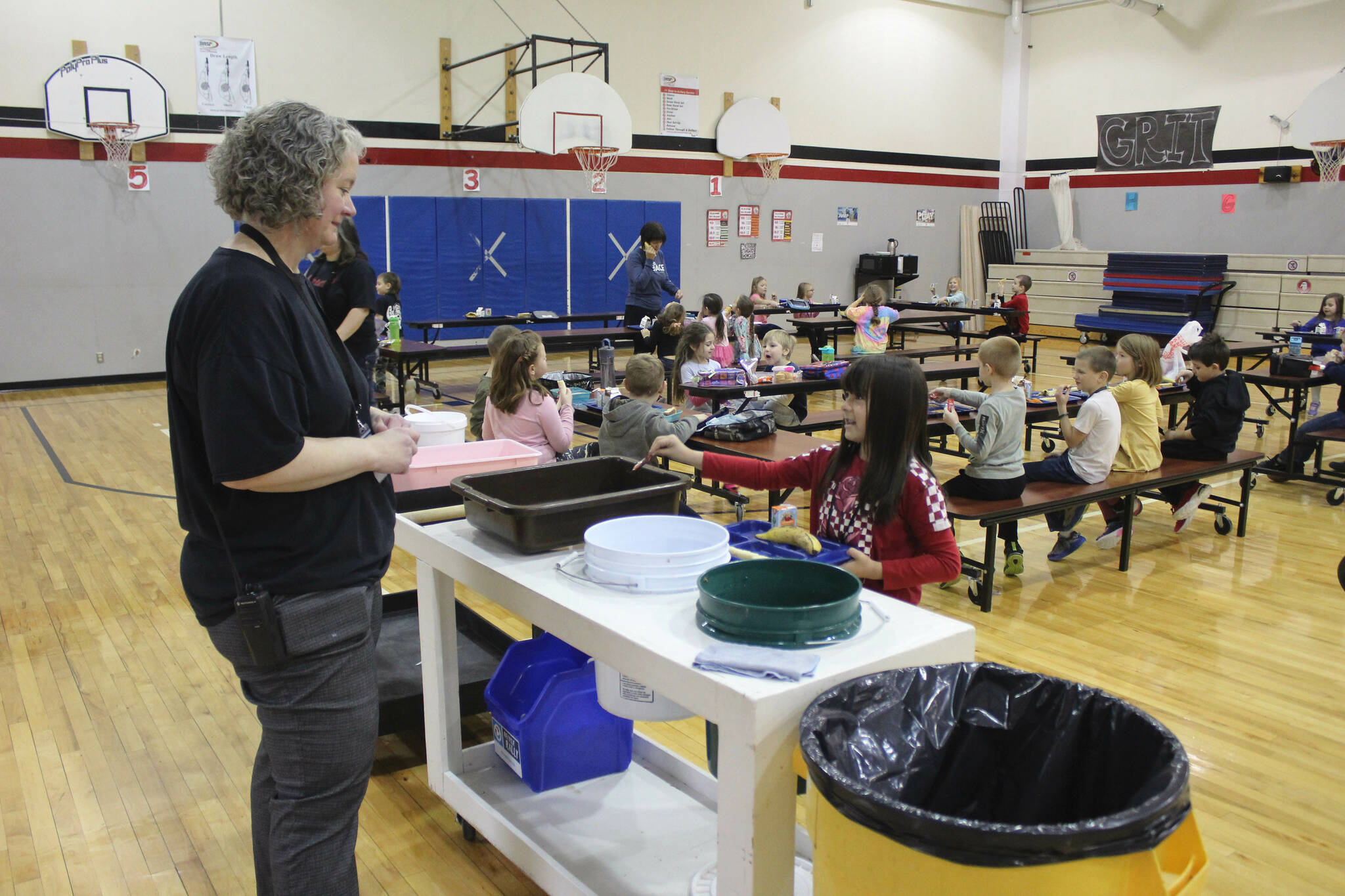 Principal Denise Kelly helps Grecia Martinez Sandstrom, second grade, dispose of lunch materials at Sterling Elementary School on Thursday, Nov. 10, 2022, in Sterling, Alaska. (Ashlyn O’Hara/Peninsula Clarion)