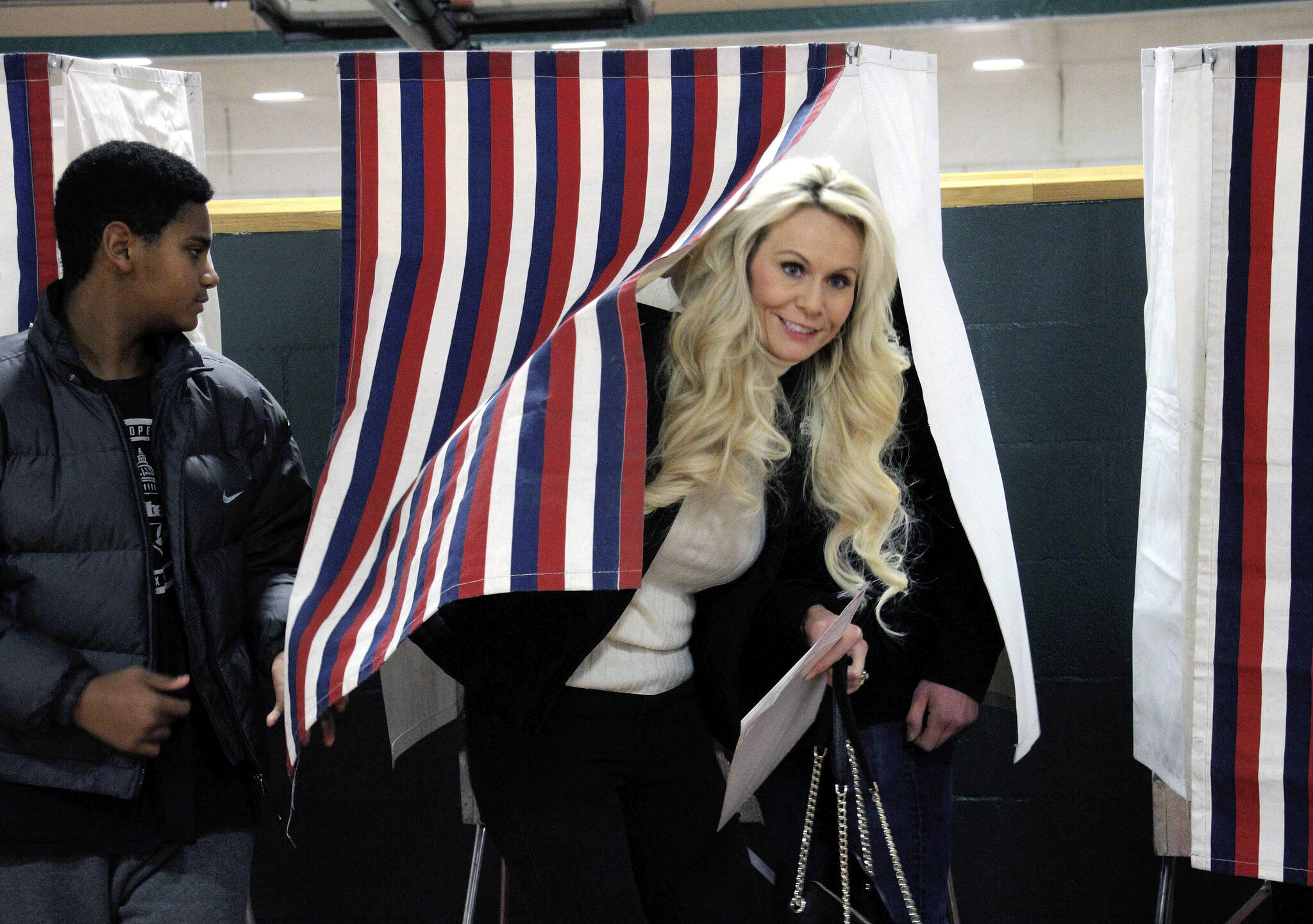 U.S. Senate candidate Kelly Tshibaka, a Republican, emerges from a voting booth with her son, Joseph, after casting her ballot Tuesday, Nov. 8, 2022, in Anchorage, Alaska. Tshibaka is trying to unseat U.S. Sen. Lisa Murkowski, also a Republican, in the general election. Also in the race is Democrat Pat Chesbro. (AP Photo/Mark Thiessen)