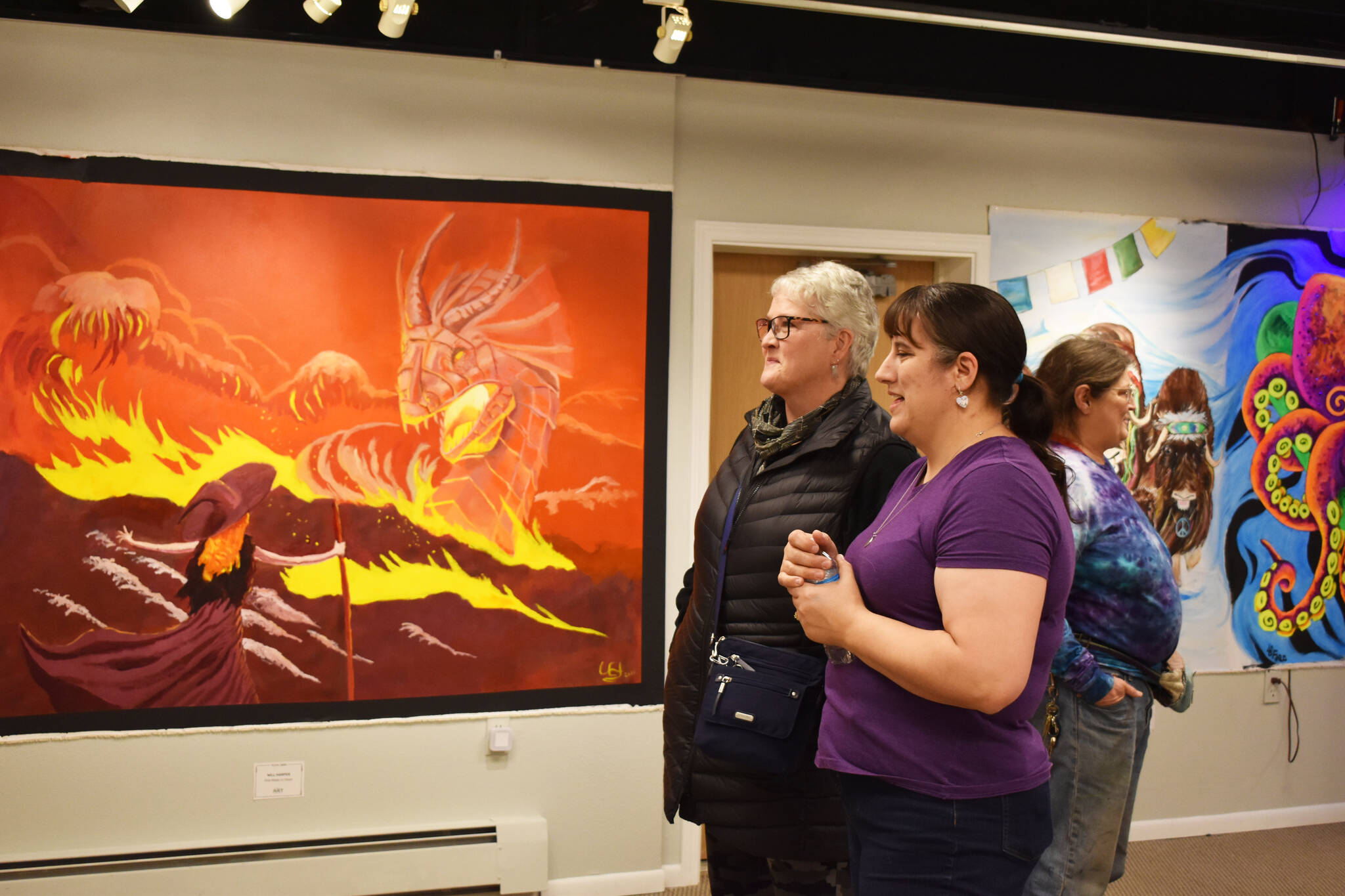 Theresa Ritter, an artist with a piece in the exhibition, speaks to an attendee of the Mural 2022 opening reception at Kenai Art Center in Kenai, Alaska, on Thursday, Nov. 10, 2022. (Jake Dye/Peninsula Clarion)