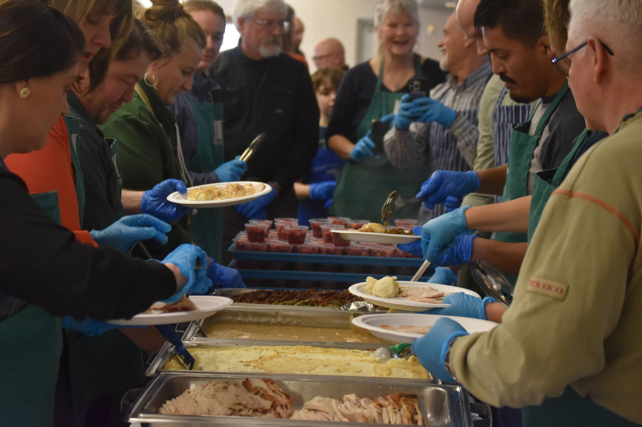Volunteers from Hilcorp plate food on Friday, Nov. 18, 2022, at the Area-Wide Senior Dinner at Kenai Seniors Center in Kenai, Alaska. (Jake Dye/Peninsula Clarion)