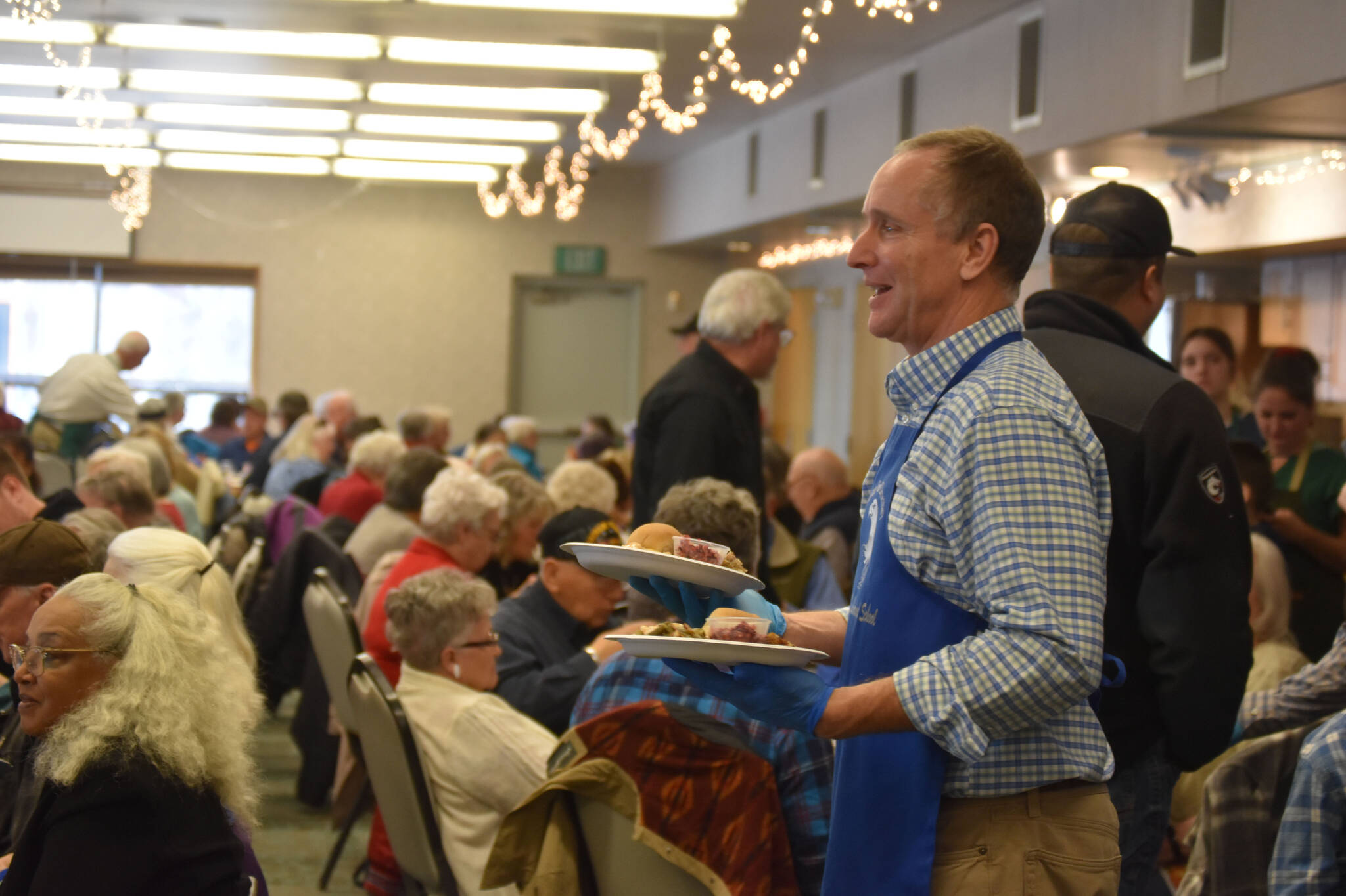 Mountain View Elementary School Principal Karl Kircher distributes dinners to seniors on Friday, Nov. 18, 2022, at the Area-Wide Senior Dinner at Kenai Seniors Center in Kenai, Alaska. (Jake Dye/Peninsula Clarion)