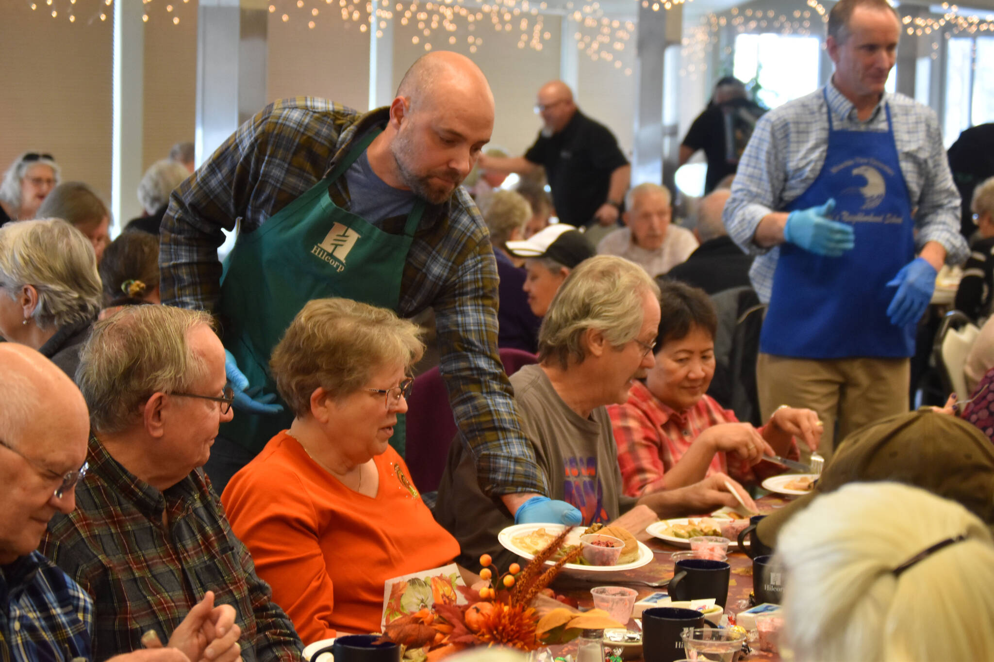 A volunteer from Hilcorp distributes dinners to seniors on Friday, Nov. 18, 2022, at the Area-Wide Senior Dinner at Kenai Seniors Center in Kenai, Alaska. (Jake Dye/Peninsula Clarion)