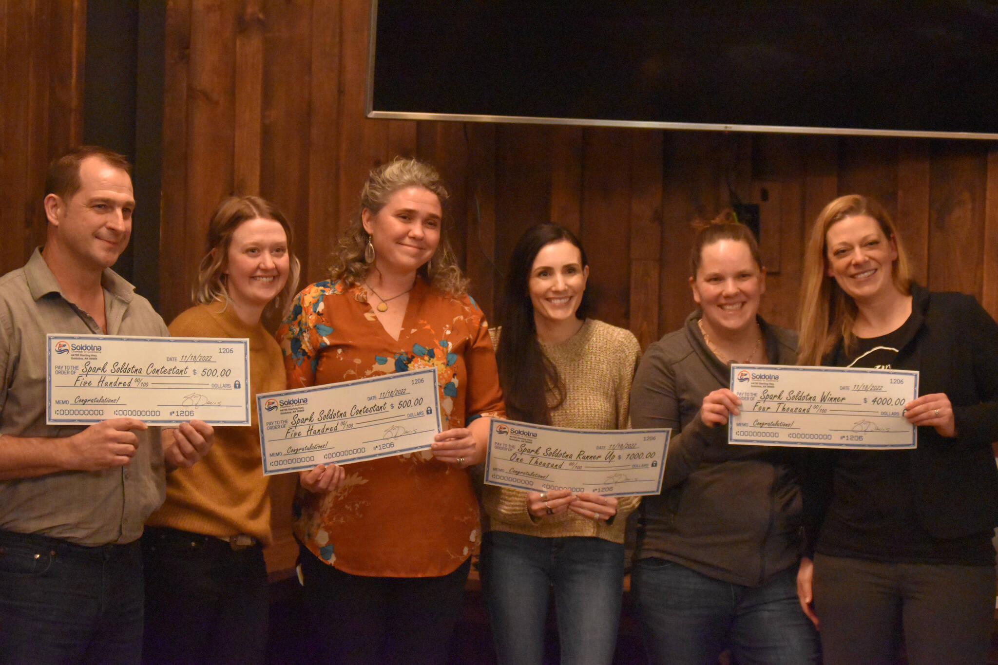 From left, contestants Richard C. Rogers, Anastasia Scollon, Willow King, JaNae Saltzgiver, Samantha Pyfer and Anna Mercier are seen with their winnings at the Spark Soldotna Shark Tank Event on Friday, Nov. 18, 2022, at The Lone Moose Lodge in Soldotna, Alaska. (Jake Dye/Peninsula Clarion)