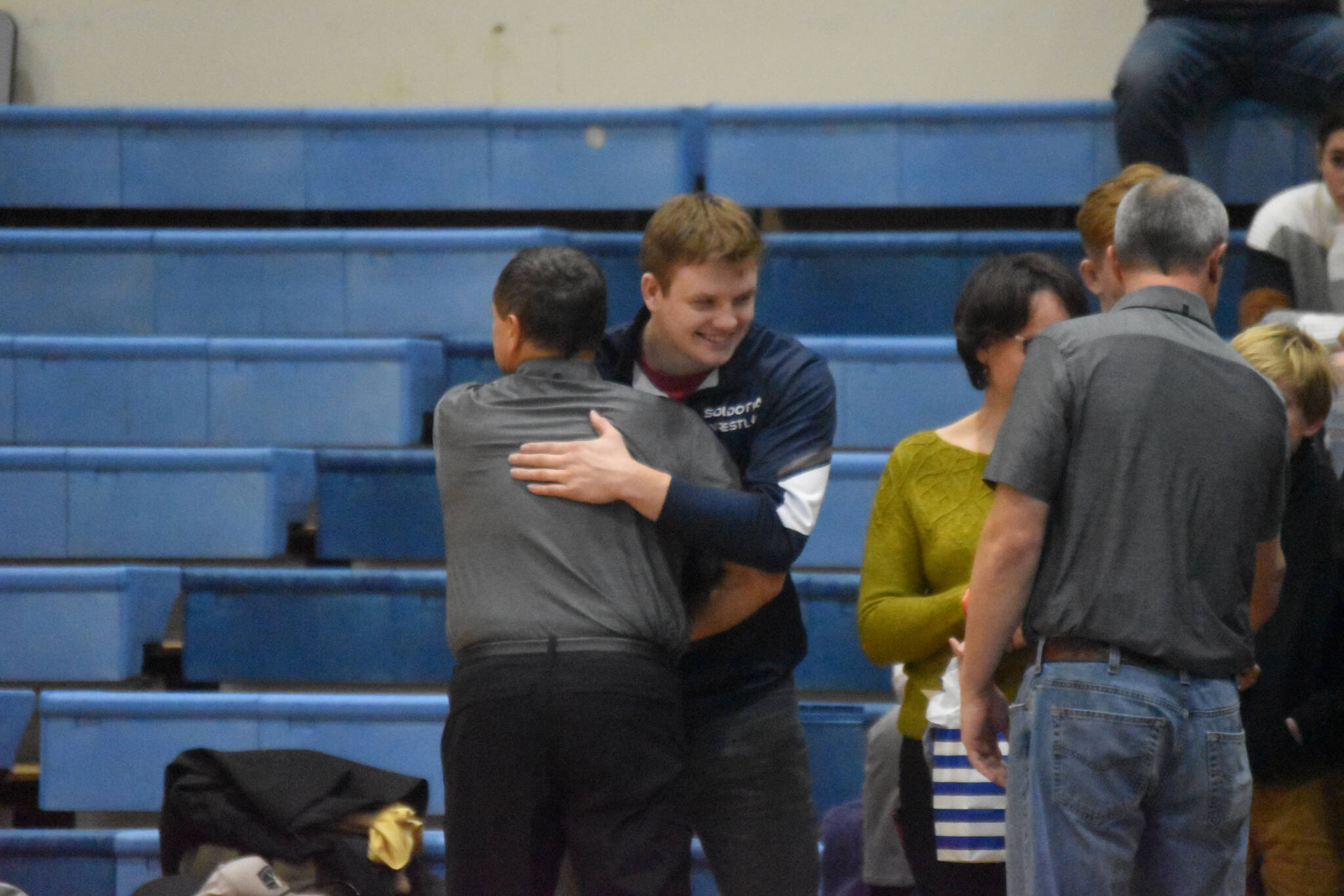 Liam Babitt hugs his coach after being honored during Senior Night at a duel wrestling meet on Tuesday, Nov. 22, 2022, at Soldotna High School in Soldotna, Alaska. (Jake Dye/Peninsula Clarion)