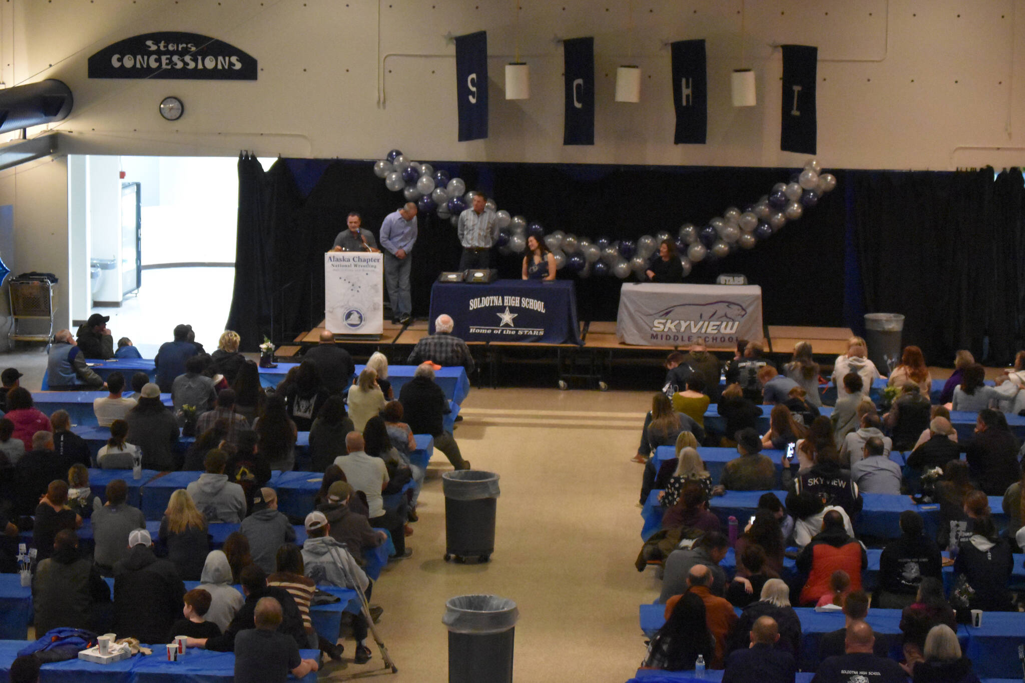 Hundreds of attendees view the induction of Tela O’Donnell-Bacher and Neldon Gardner to the National Wrestling Hall of Fame following a duel wrestling meet on Tuesday, Nov. 22, 2022, at Soldotna High School in Soldotna, Alaska. (Jake Dye/Peninsula Clarion)