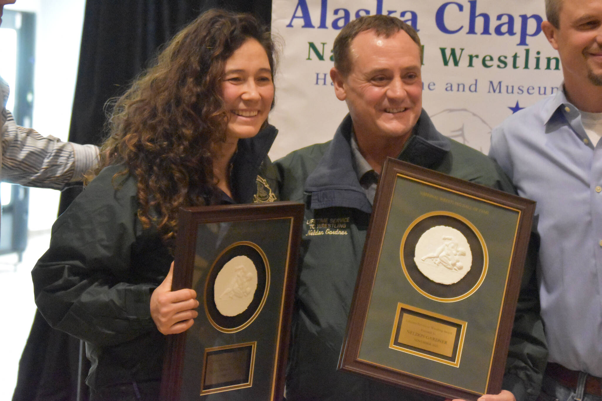 Tela O’Donnell-Bacher and Neldon Gardner hold their plaques after being inducted into the National Wrestling Hall of Fame following a duel wrestling meet on Tuesday, Nov. 22, 2022, at Soldotna High School in Soldotna, Alaska. (Jake Dye/Peninsula Clarion)