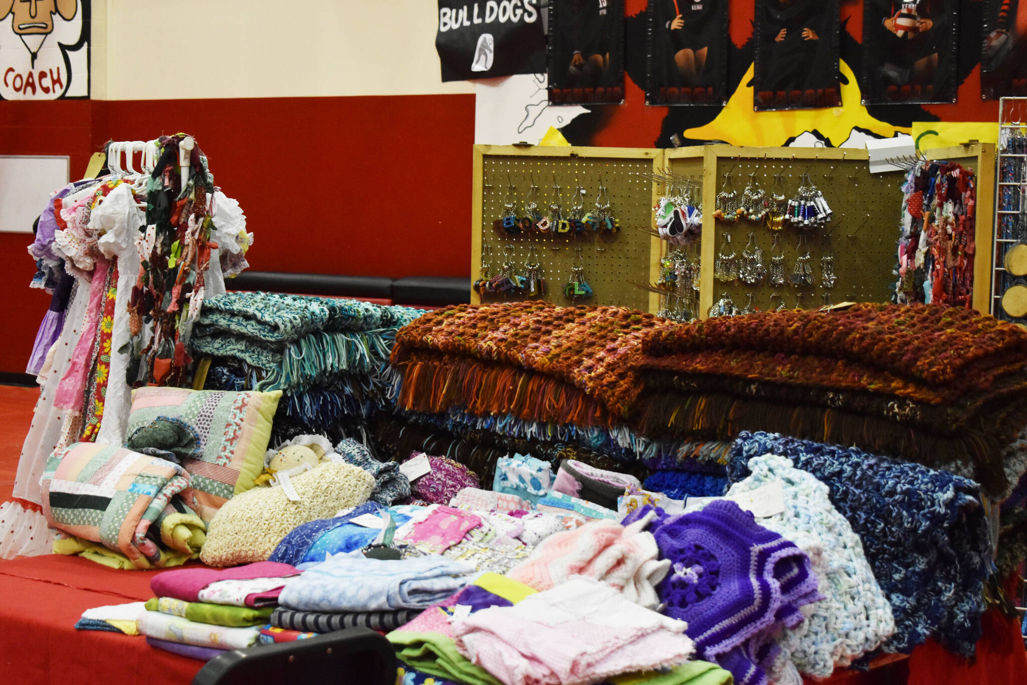 Blankets and other knit and crafted cloth products are seen, ready to be sold, ahead of the Kenai Arts & Crafts Fair during early set up at Kenai Central High School in Kenai, Alaska, on Wednesday, Nov. 23, 2022. (Jake Dye/Peninsula Clarion)
