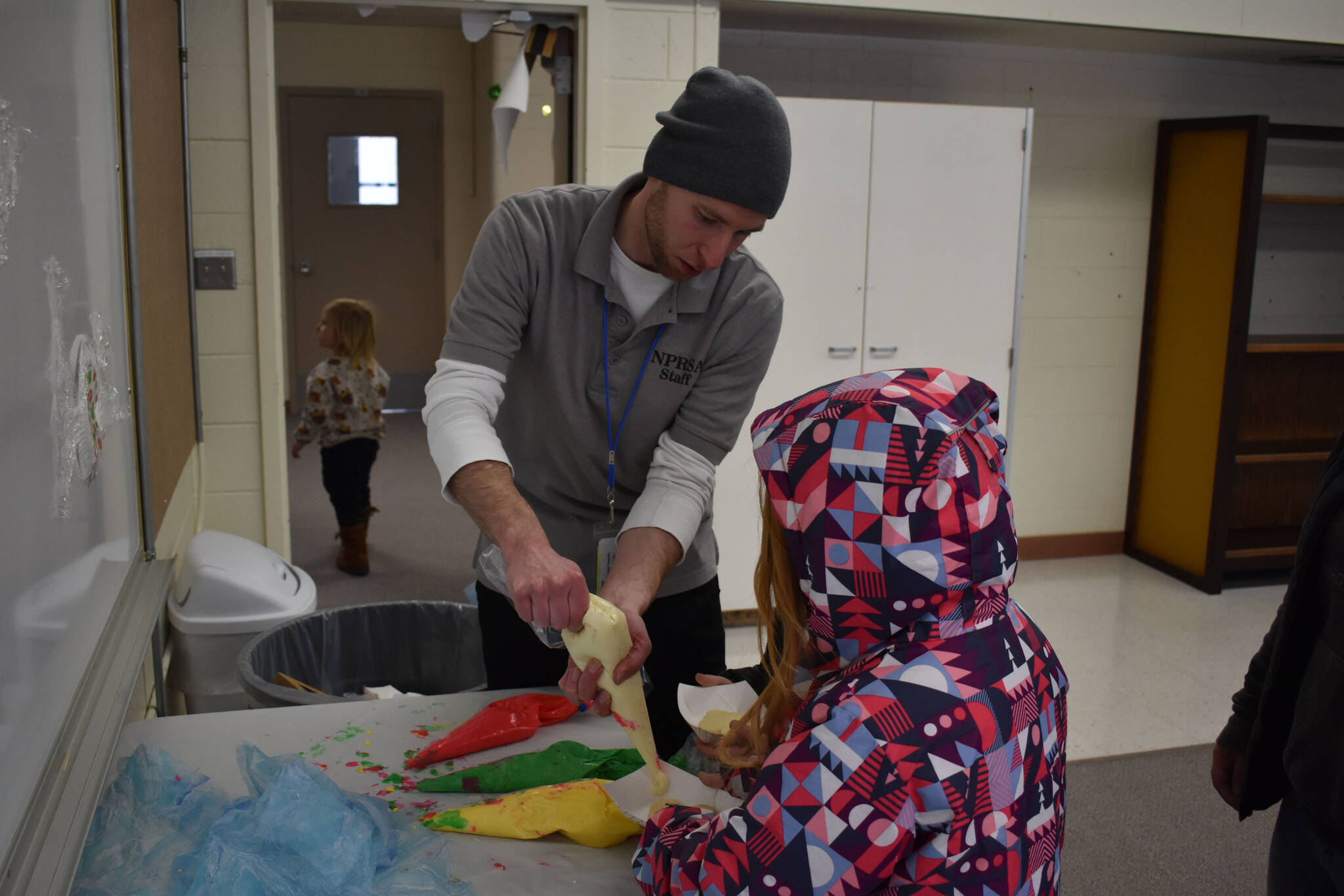 Children collect frosting for decorating Christmas cookies, part of Christmas Comes to Nikiski festivities on Saturday, Dec. 3, 2022, at Nikiski Community Recreation Center in Nikiski, Alaska. (Jake Dye/Peninsula Clarion)