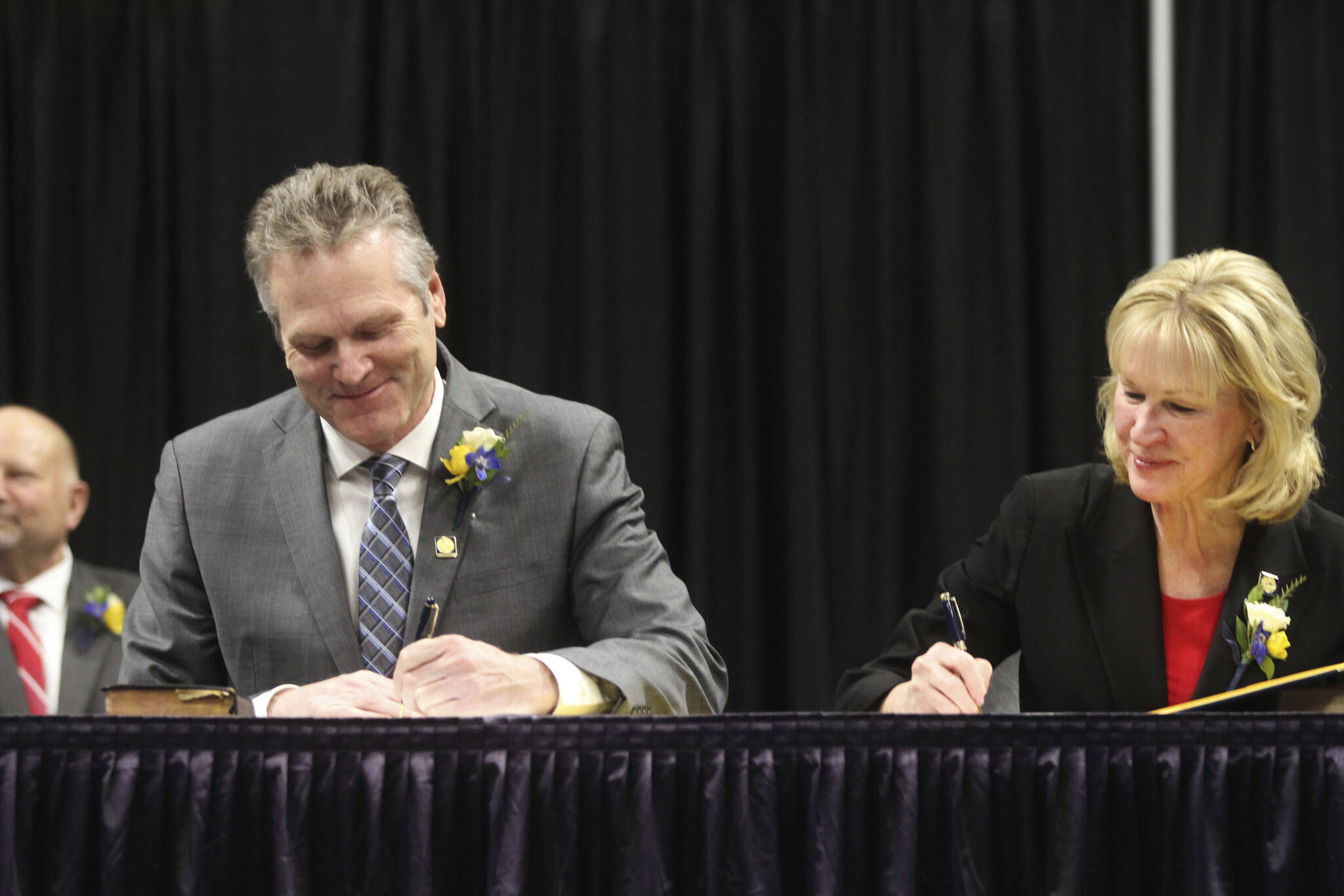 Gov. Mike Dunleavy, seated left, and Lt. Gov. Nancy Dahlstrom sign their oaths of office during the inauguration ceremony, Monday, Dec. 5, 2022, in Anchorage, Alaska. Dunleavy, a Republican, last month became the first Alaska governor since Democrat Tony Knowles in 1998 to win back-to-back terms. (AP Photo/Mark Thiessen)