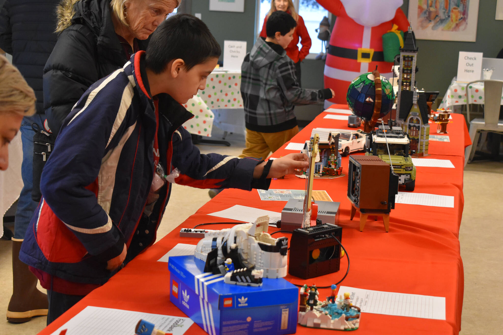 A potential buyer checks out the Lego Fender Stratocaster during Bark, Block and Bowl on Saturday, Dec. 10, 2022, at the Kenai Peninsula Food Bank in Soldotna, Alaska. (Jake Dye/Peninsula Clarion)