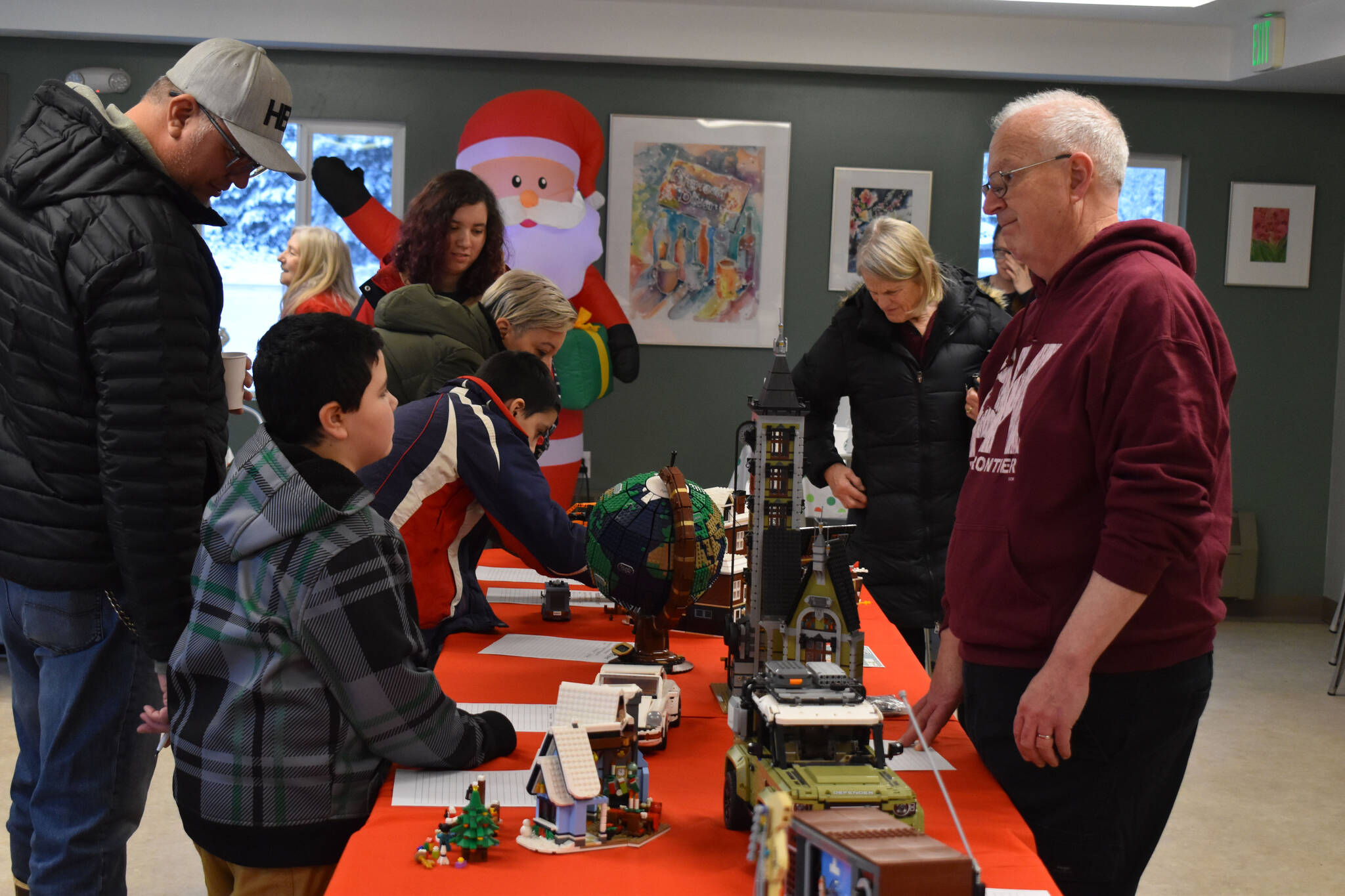 Greg Meyer speaks to a potential buyer of the Lego sets he built as they are put on auction during Bark, Block and Bowl on Saturday, Dec. 10, 2022, at the Kenai Peninsula Food Bank in Soldotna, Alaska. (Jake Dye/Peninsula Clarion)
