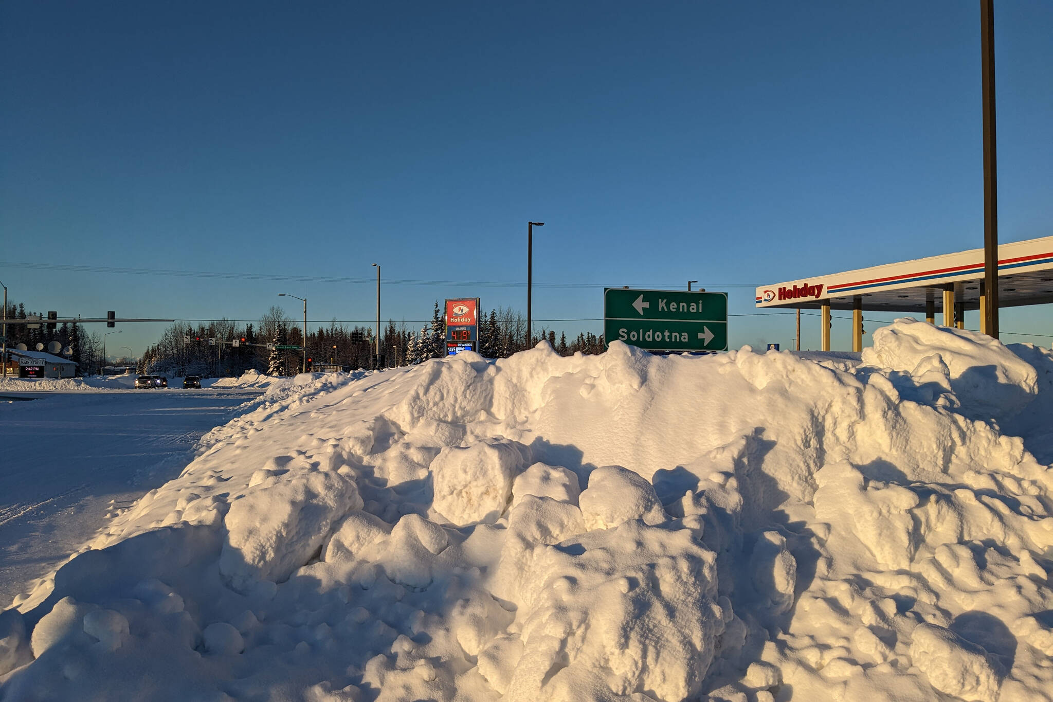 Plowed snow is piled high near the intersection of Main Street Loop and Kenai Spur Highway, Monday, Dec. 12, 2022, in Kenai, Alaska. The area received several feet of snow over the weekend. (Photo by Erin Thompson/Peninsula Clarion)