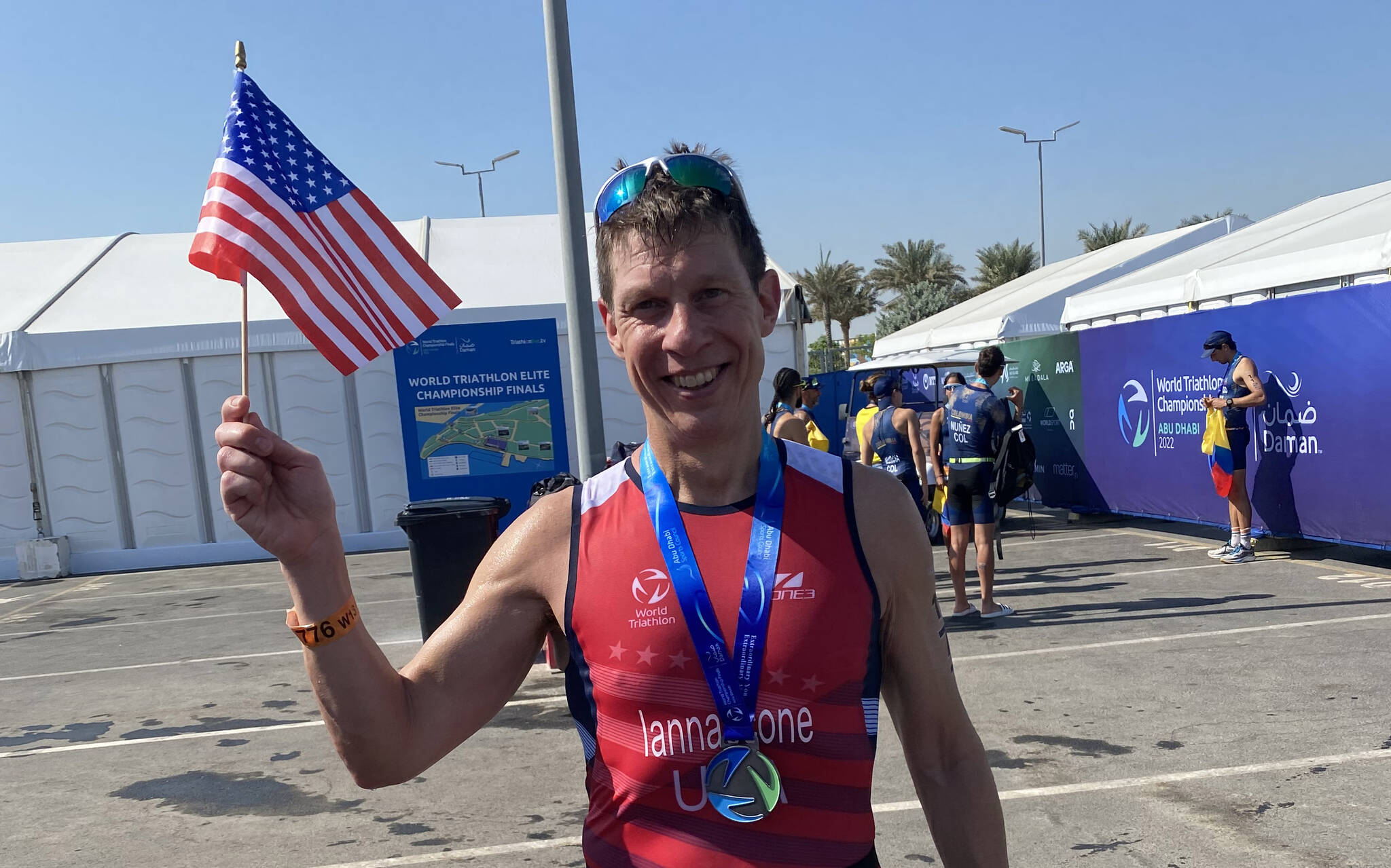Jon Iannaccone waves an American flag while wearing a medal after completing the World Triathlon Championships in Abu Dhabi, United Arab Emirates, Nov. 26, 2022. (Photo courtesy Jon Iannaccone)